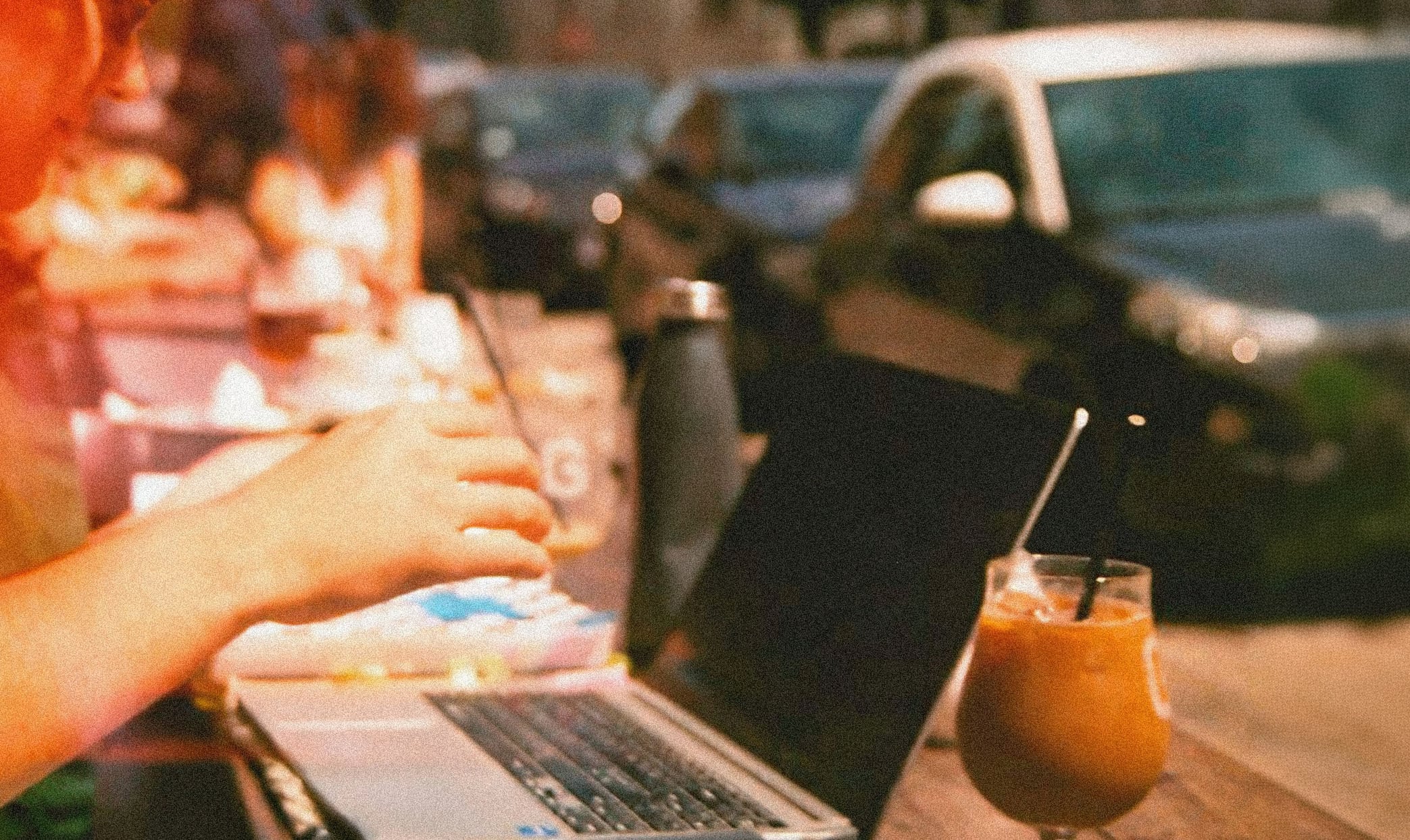 Person, der arbejder på en bærbar fra en café under en campingtur. Billede, der illustrerer, hvordan forretningsrejser kan kombineres med ferie, fjernarbejde og fleksibilitet.