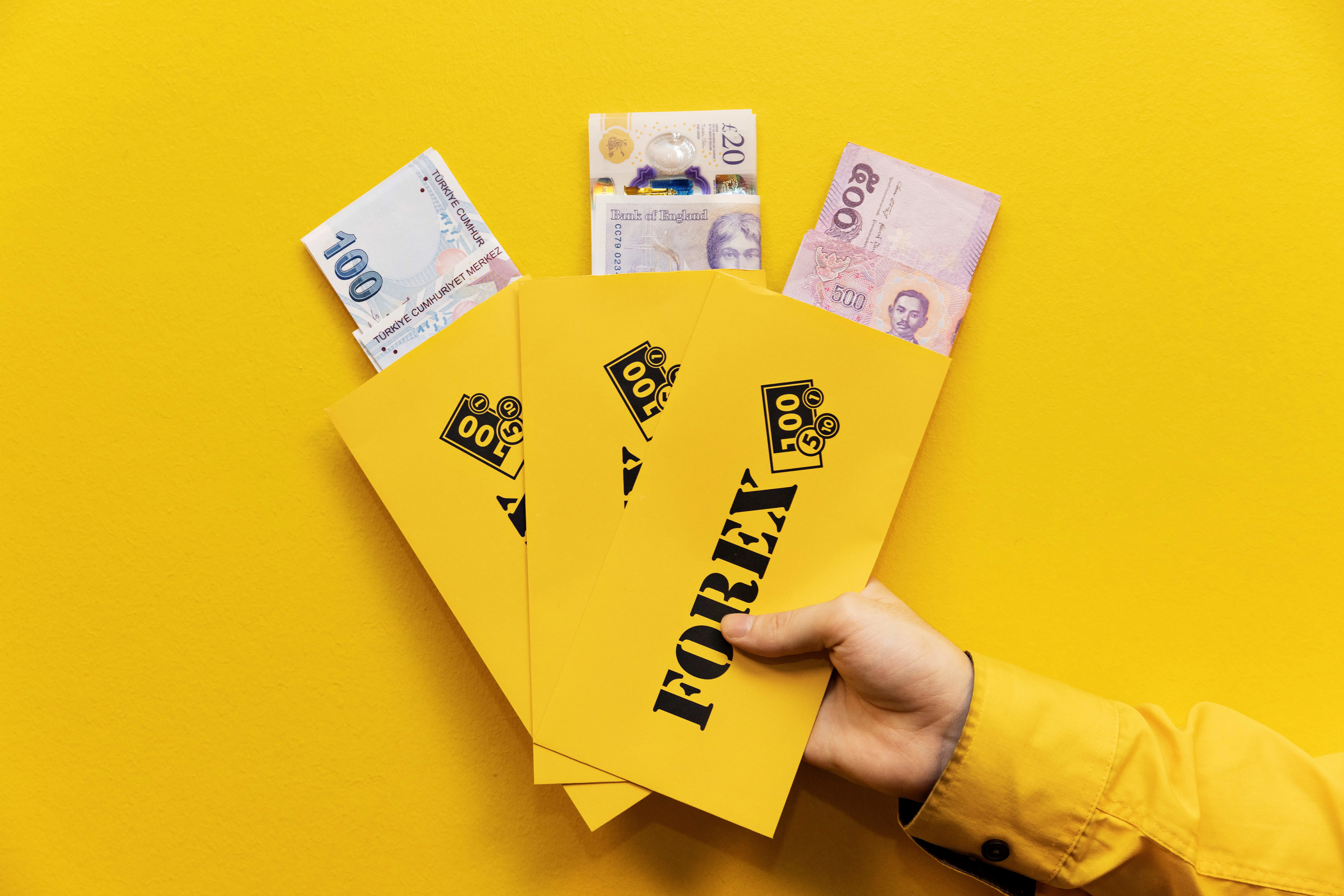 FOREX valutakonvolutter holdes af en hånd med rejsevaluta synlig i dem