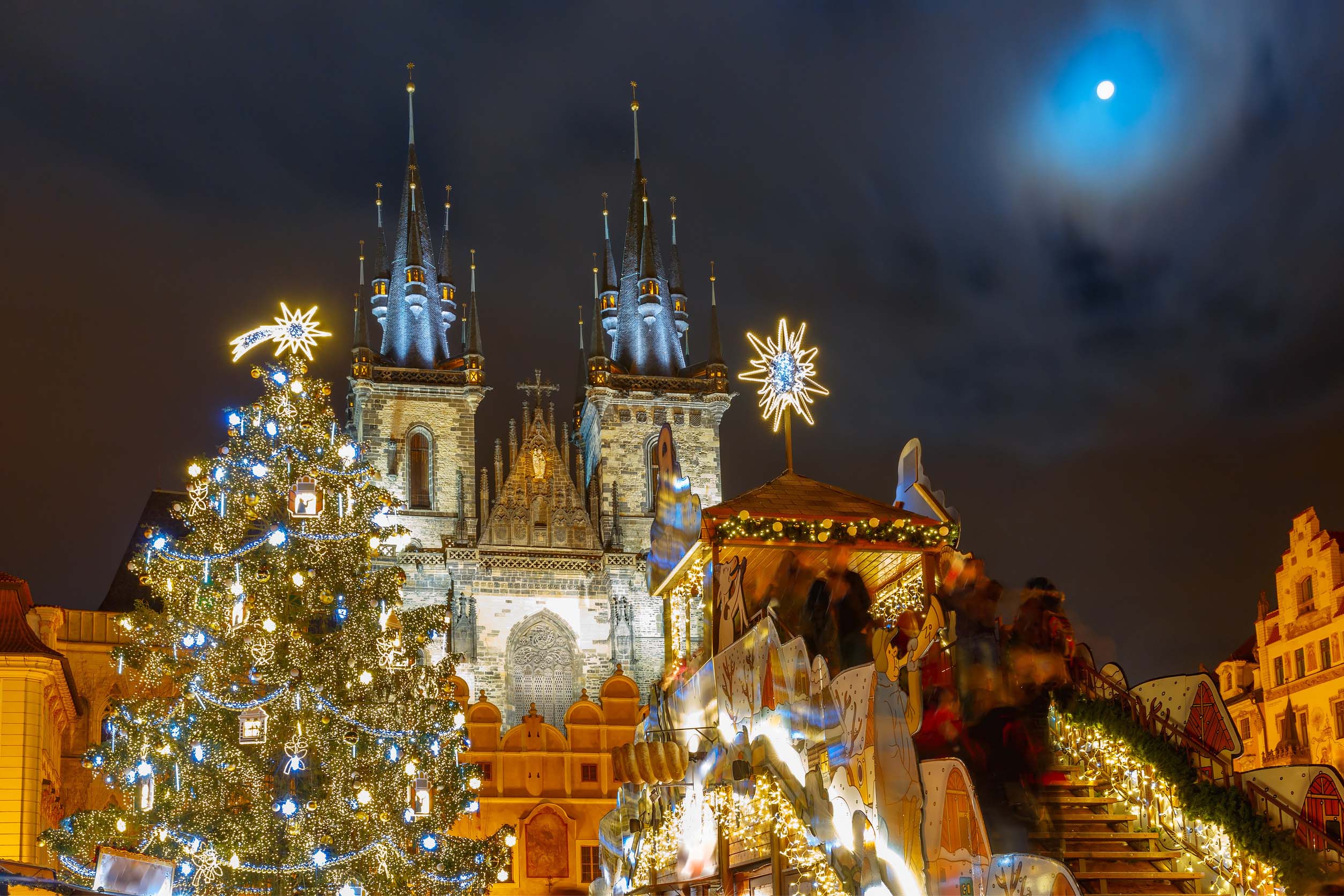 Christmas tree and festive stalls at Prague’s Old Town Square with the Church of Our Lady before Týn in the background at night