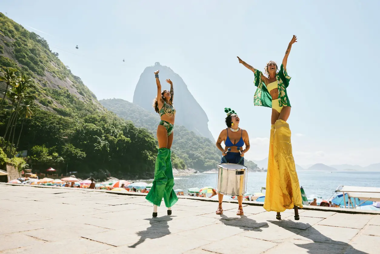 Kvinnor dansar och ler under karnivalen i Rio vid en strand