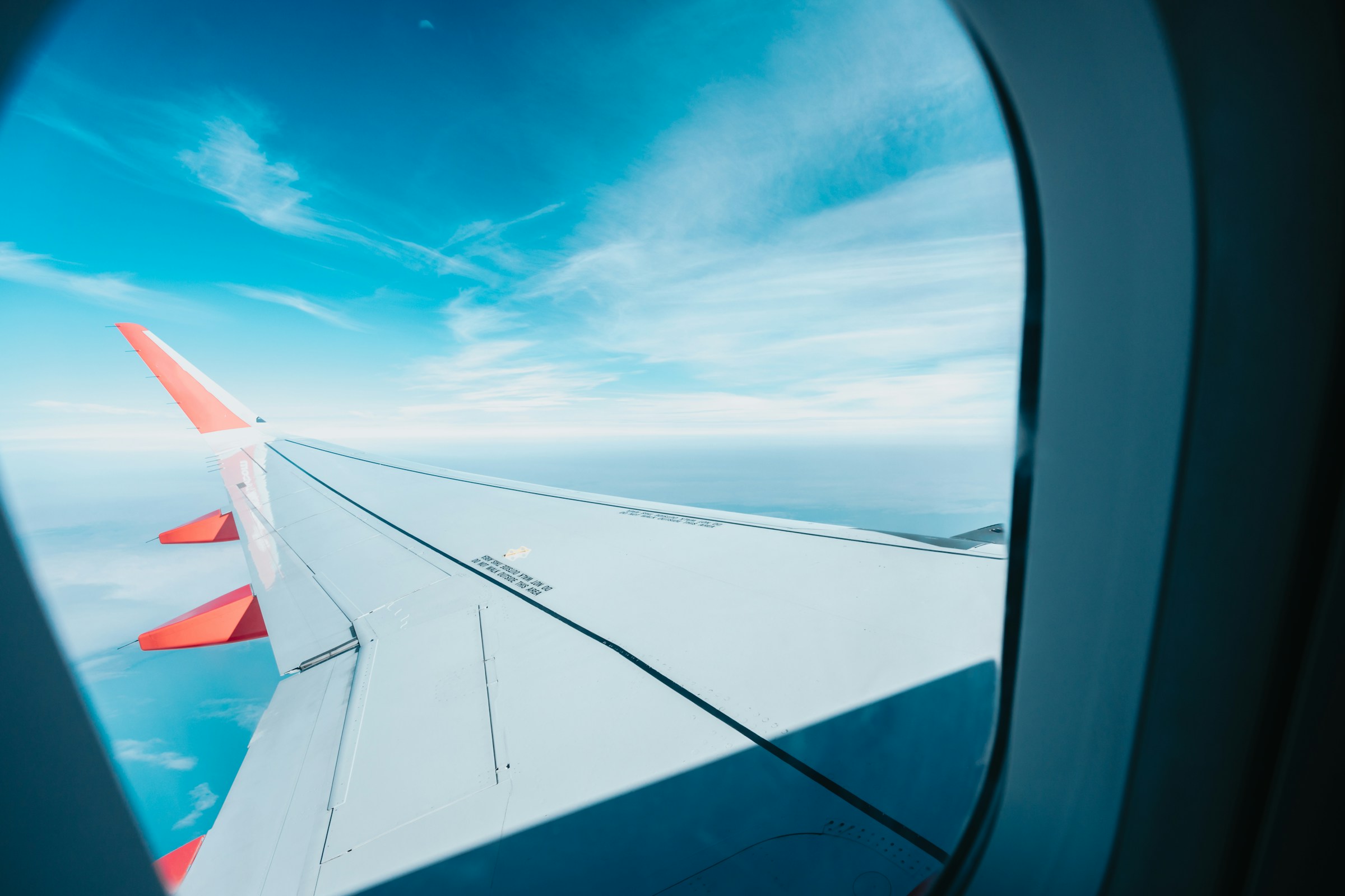 View from airplane window showing wing and clear blue sky.