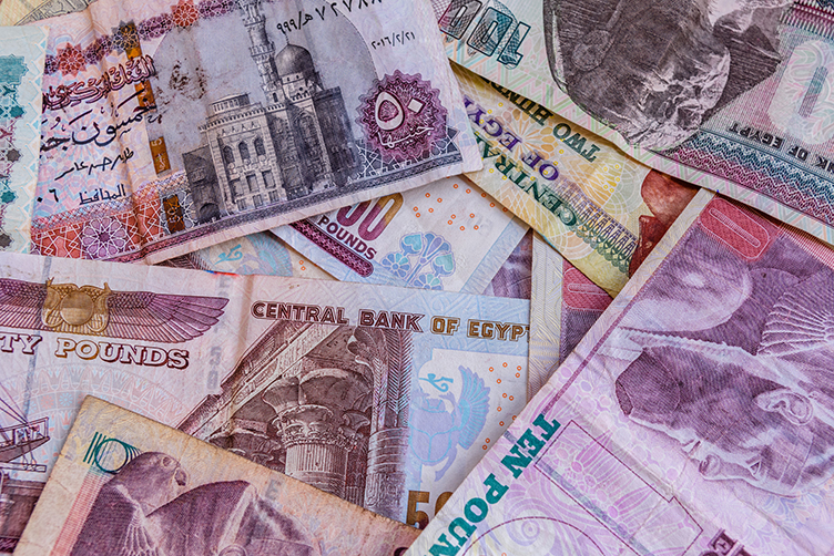 Egyptian banknotes of different denominations spread over a surface, with detailed patterns and colours.