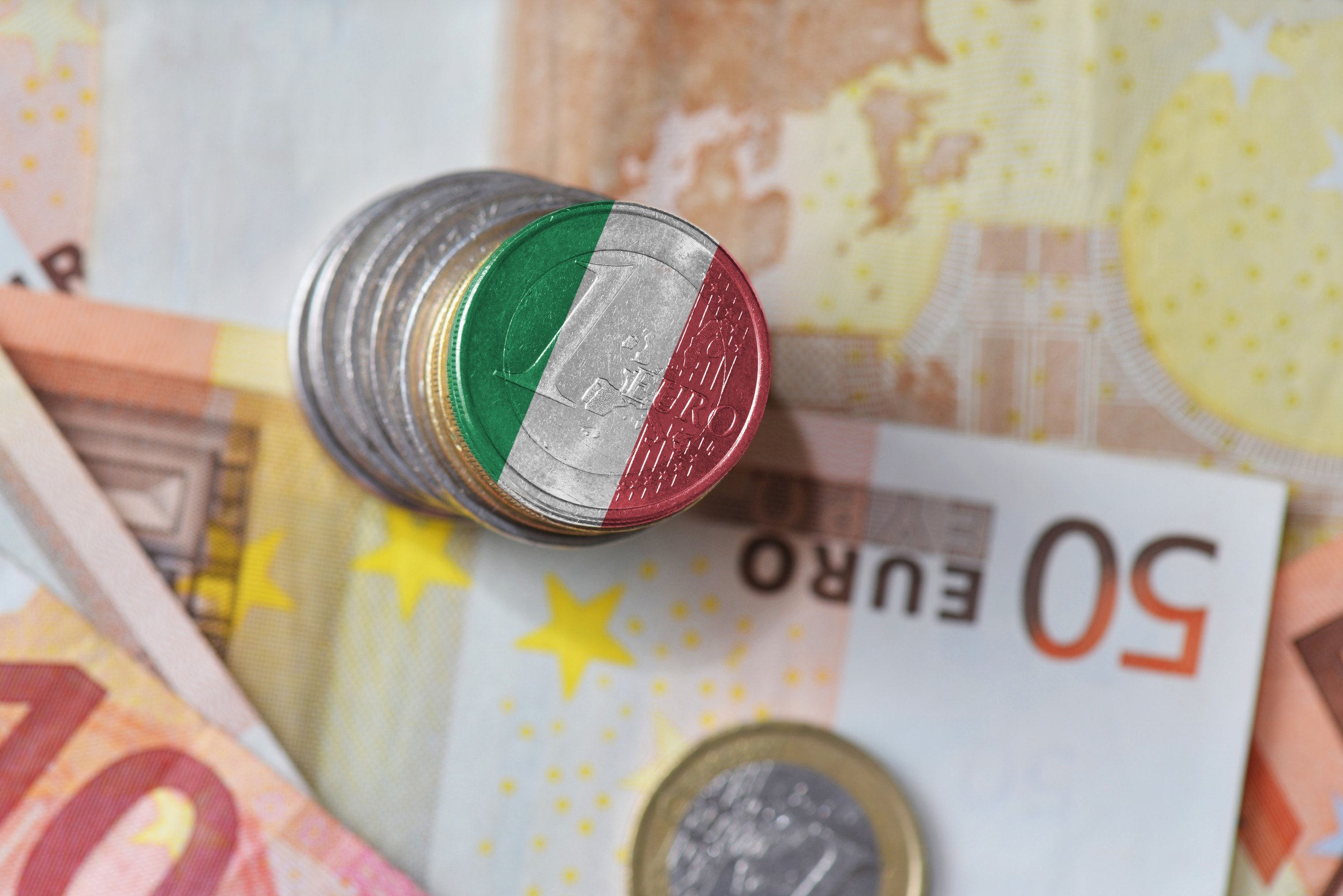 Italian euro cent coins stacked on euro banknotes, showing the flag of Italy.