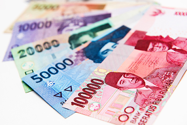 Indonesian rupiah banknotes of different denominations are scattered.