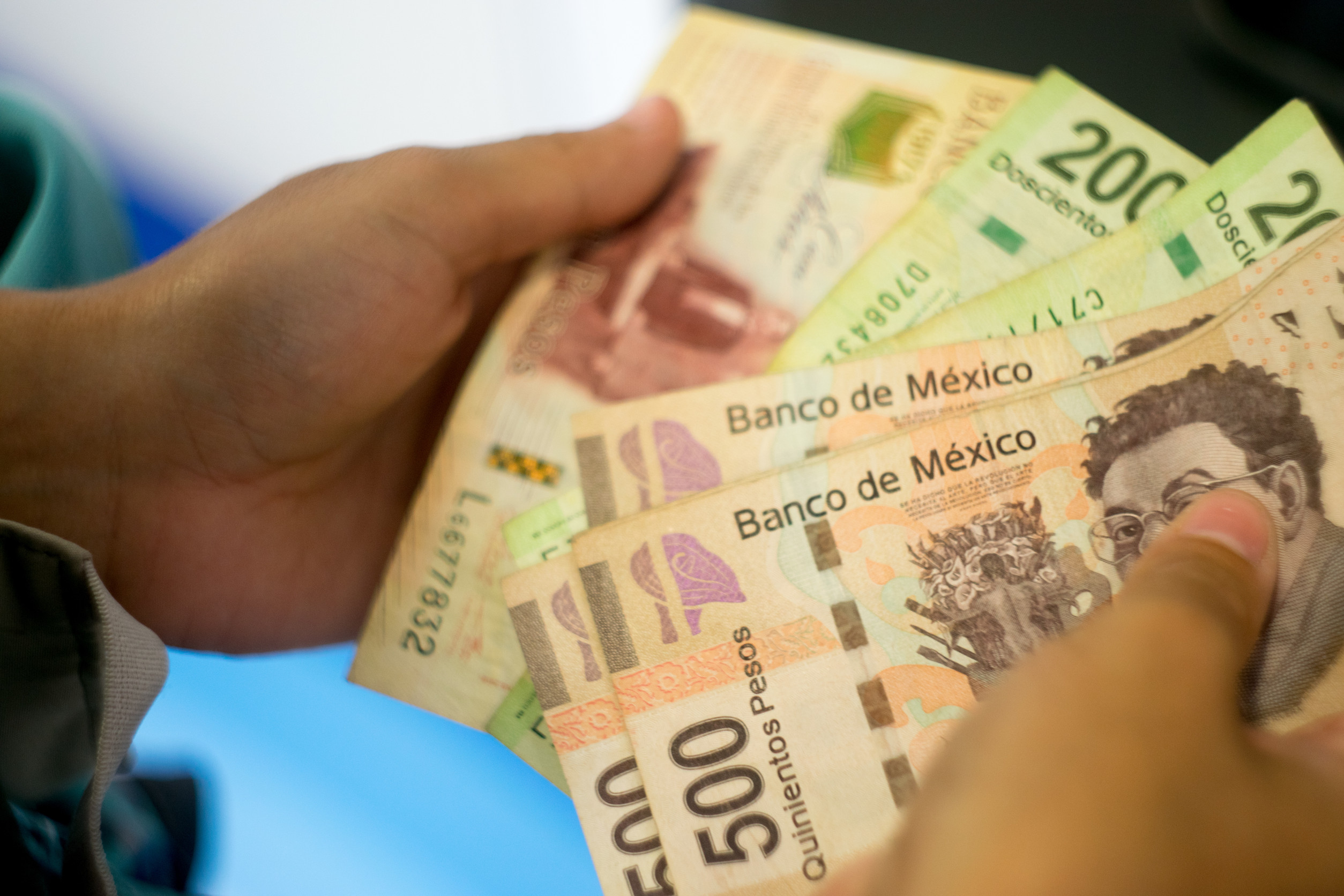 Person holds Mexican pesos in various denominations, including 500 and 200 banknotes, with the text "Banco de México".