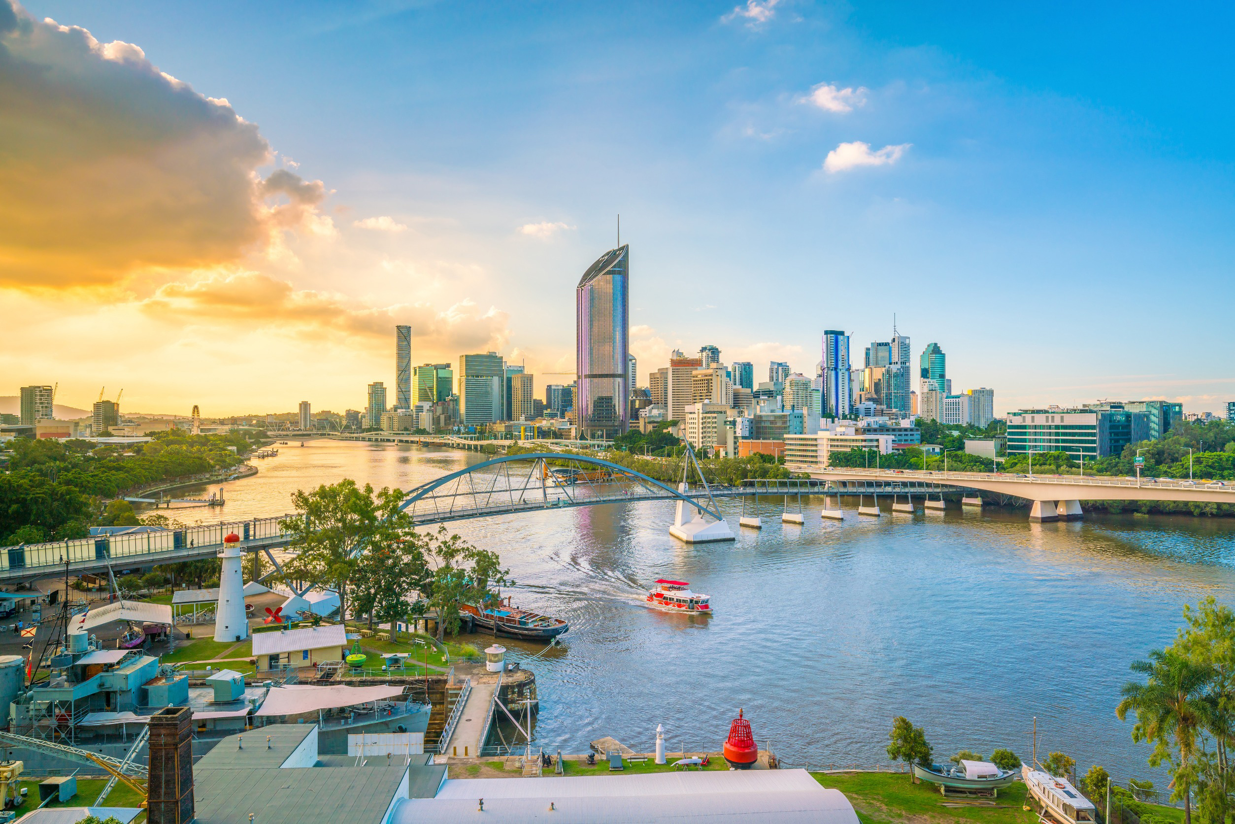 Panoramaudsigt over Brisbane-floden ved solnedgang med byens skyline og ikoniske bro i forgrunden