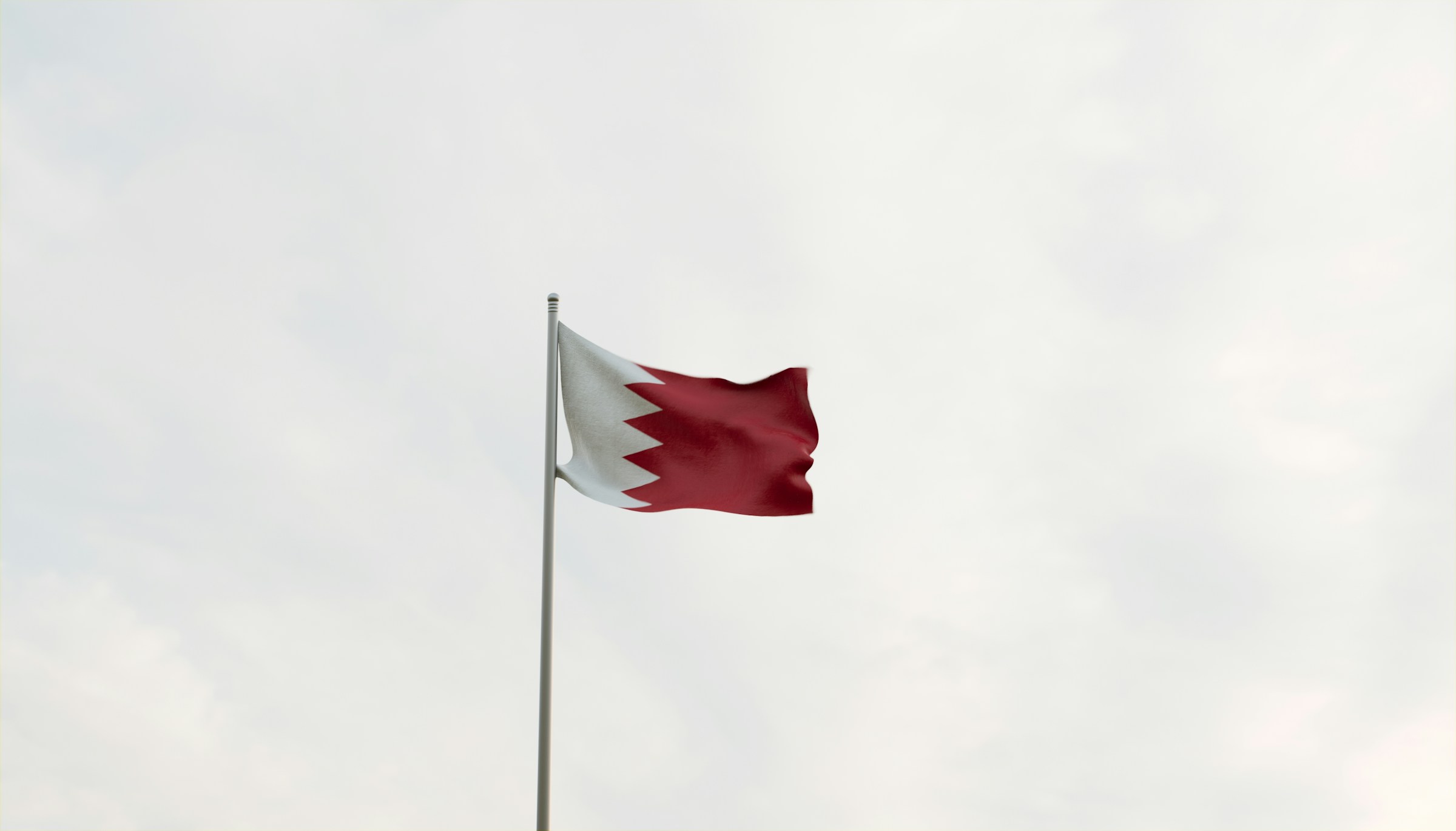 Bahrain national flag waving against a cloudy sky background.