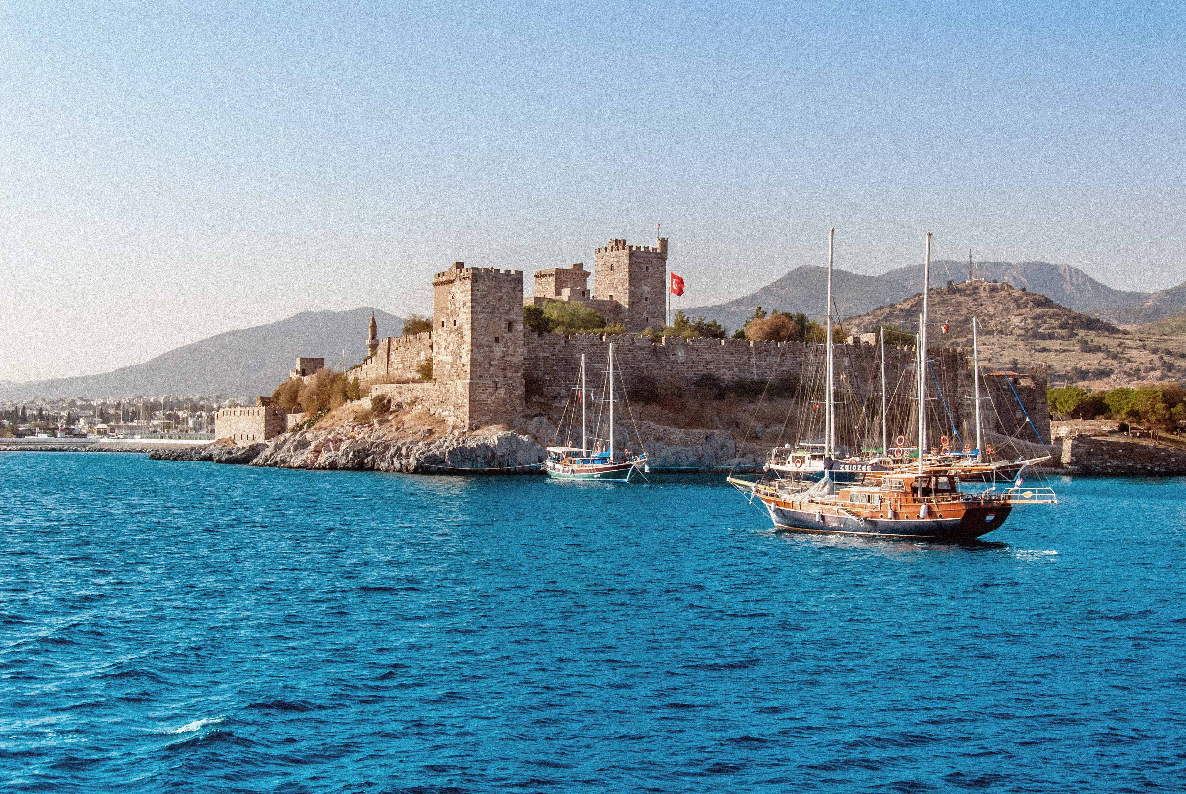 Bodrum Castle by the Sea with Sailboats in the Foreground and Mountains in the Background in Turkey