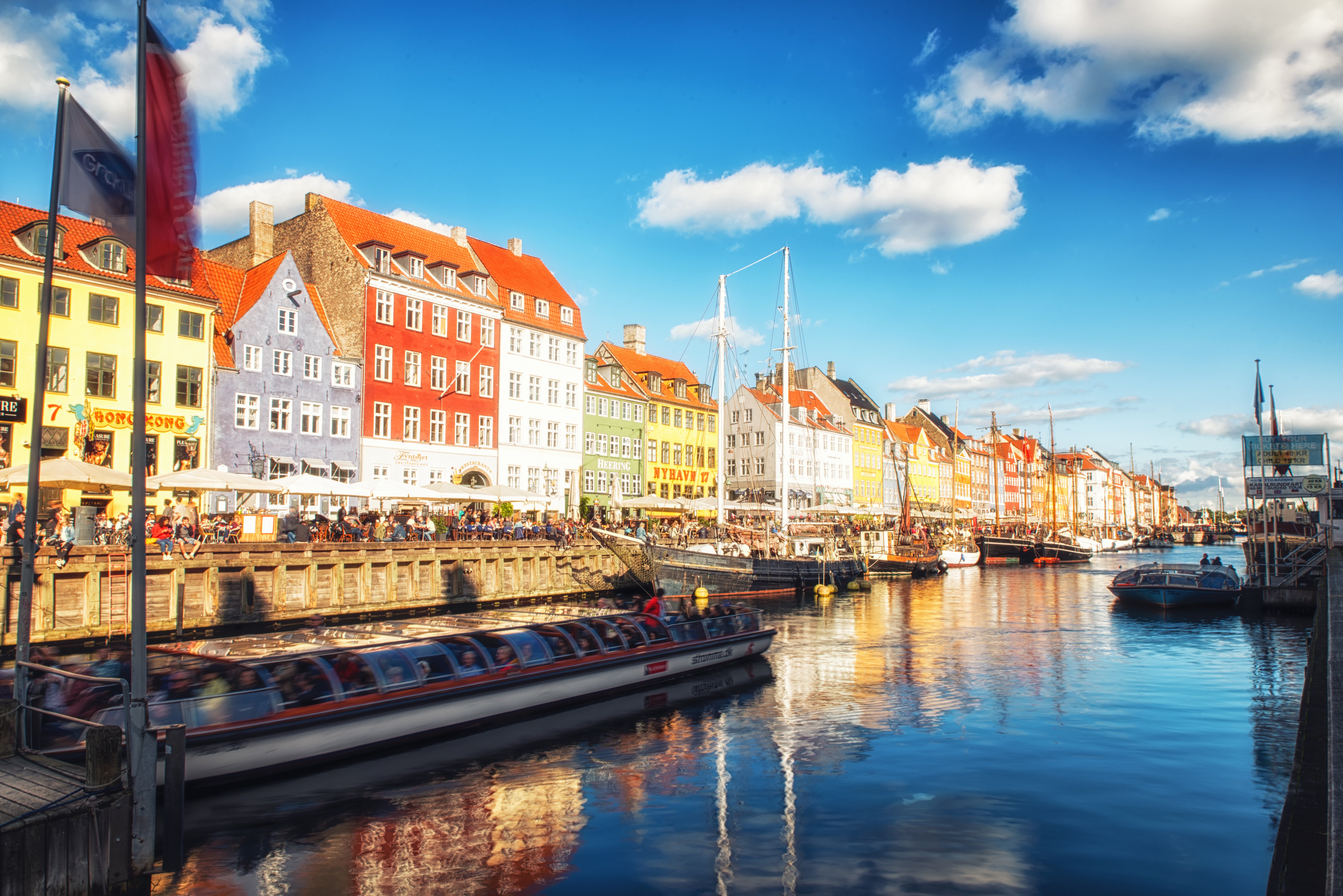 Nyhavn i København, Danmark, med farverige bygninger og kanaler fyldt med både og mennesker i solskin