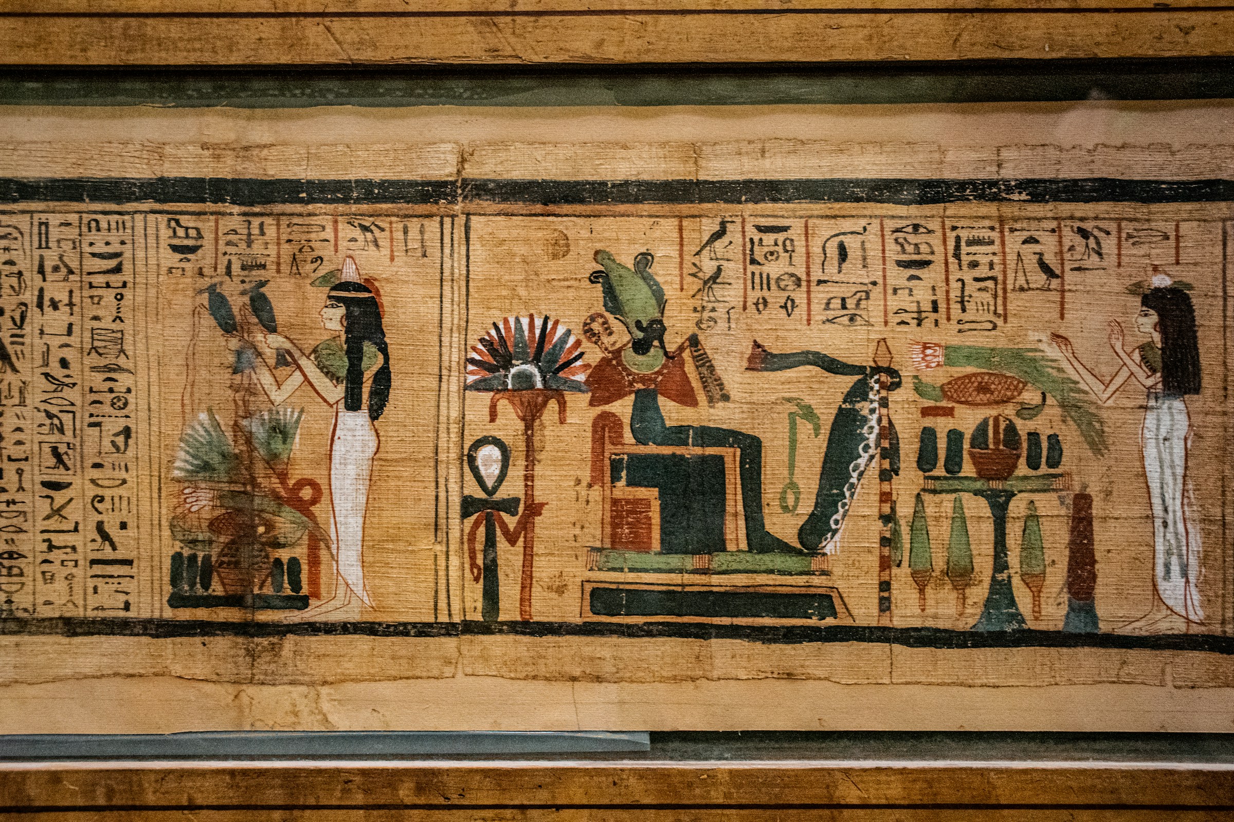 Ancient Egyptian papyrus illustration depicting deities and hieroglyphs, featuring seated god figures and standing attendants with traditional regalia.