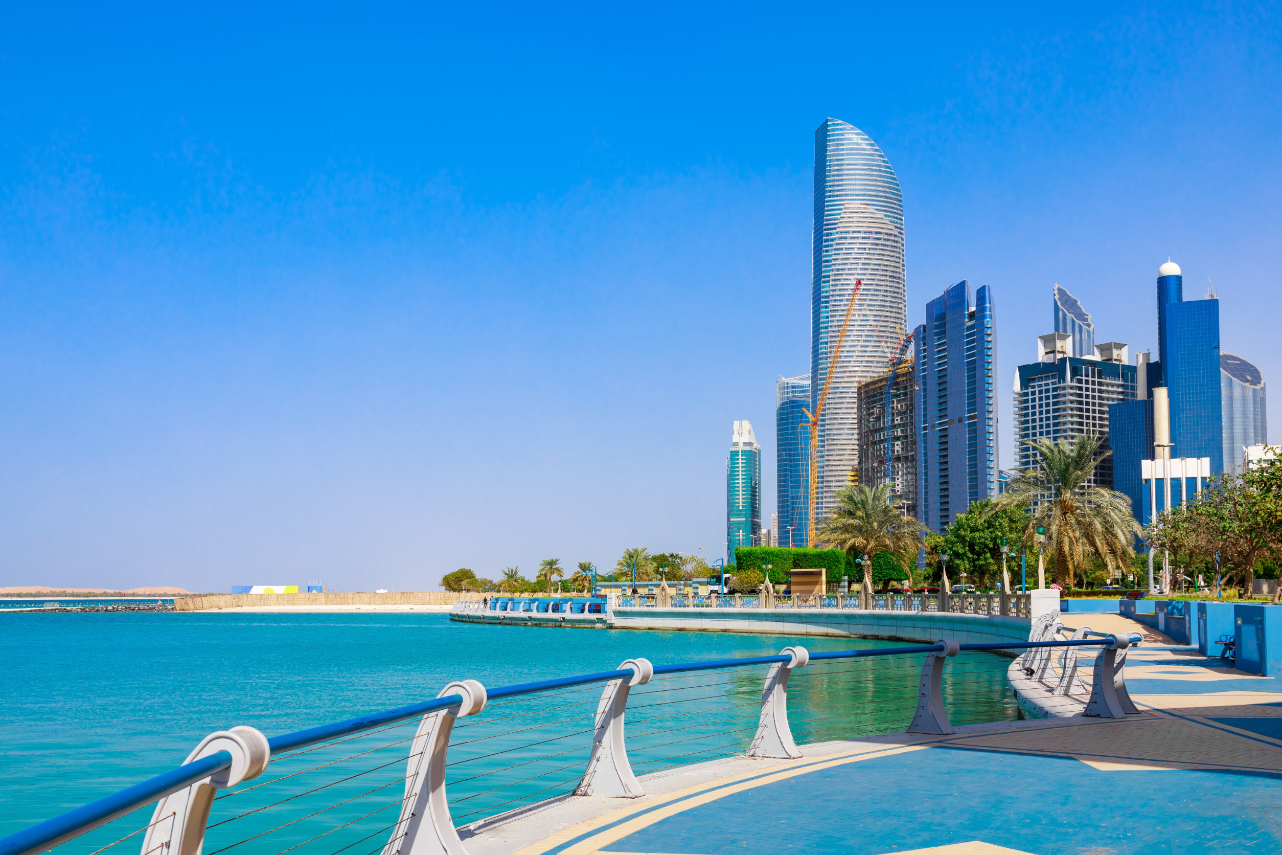 Moderne bygningslandskab og havnefront i Abu Dhabi med skyskrabere og en promenade ved det blå hav