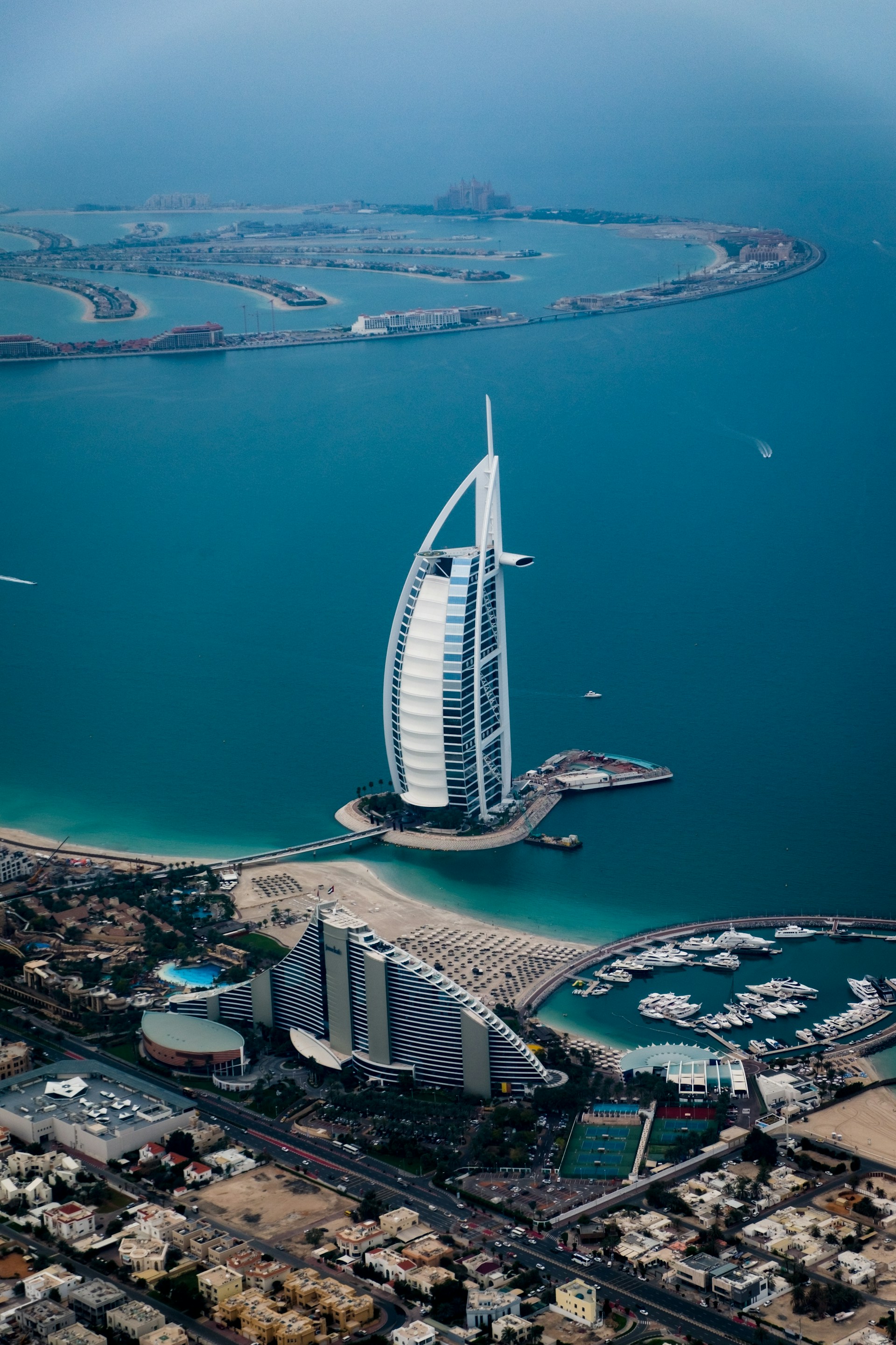 Udsigt over Burj Al Arab og Palm Jumeirah i Dubai, omgivet af det turkisfarvede hav, med luksushoteller og badestrande i forgrunden