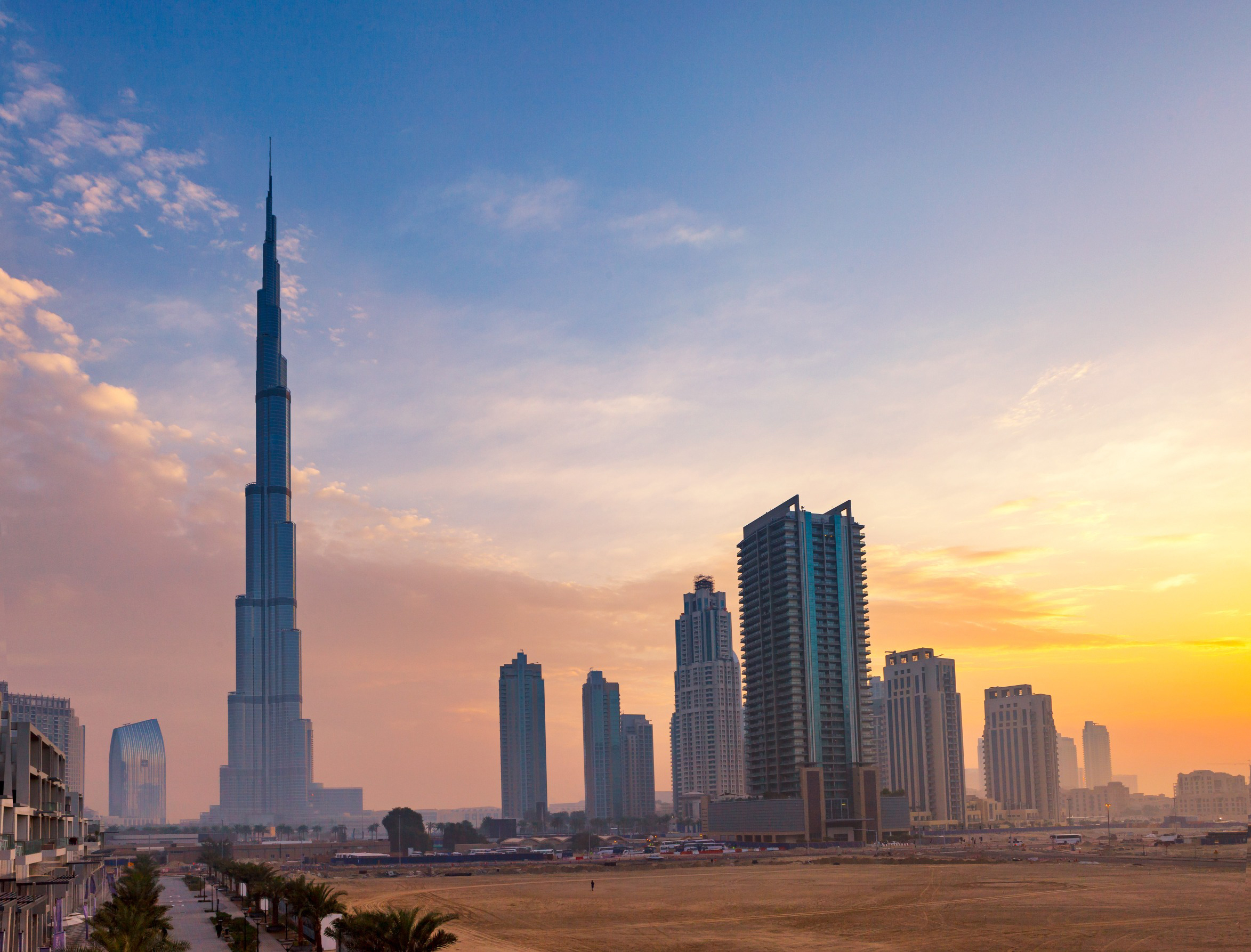 Travel to Dubai - Dubai skyline at sunset featuring the Burj Khalifa and modern skyscrapers.