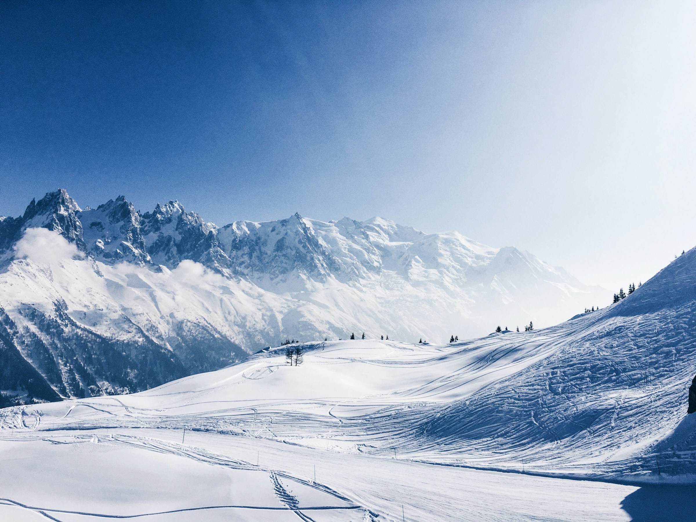 Udsigt over vinterlandskab og sneklædte dale og bjerge i Chamonix, Frankrig med blå himmel i baggrunden