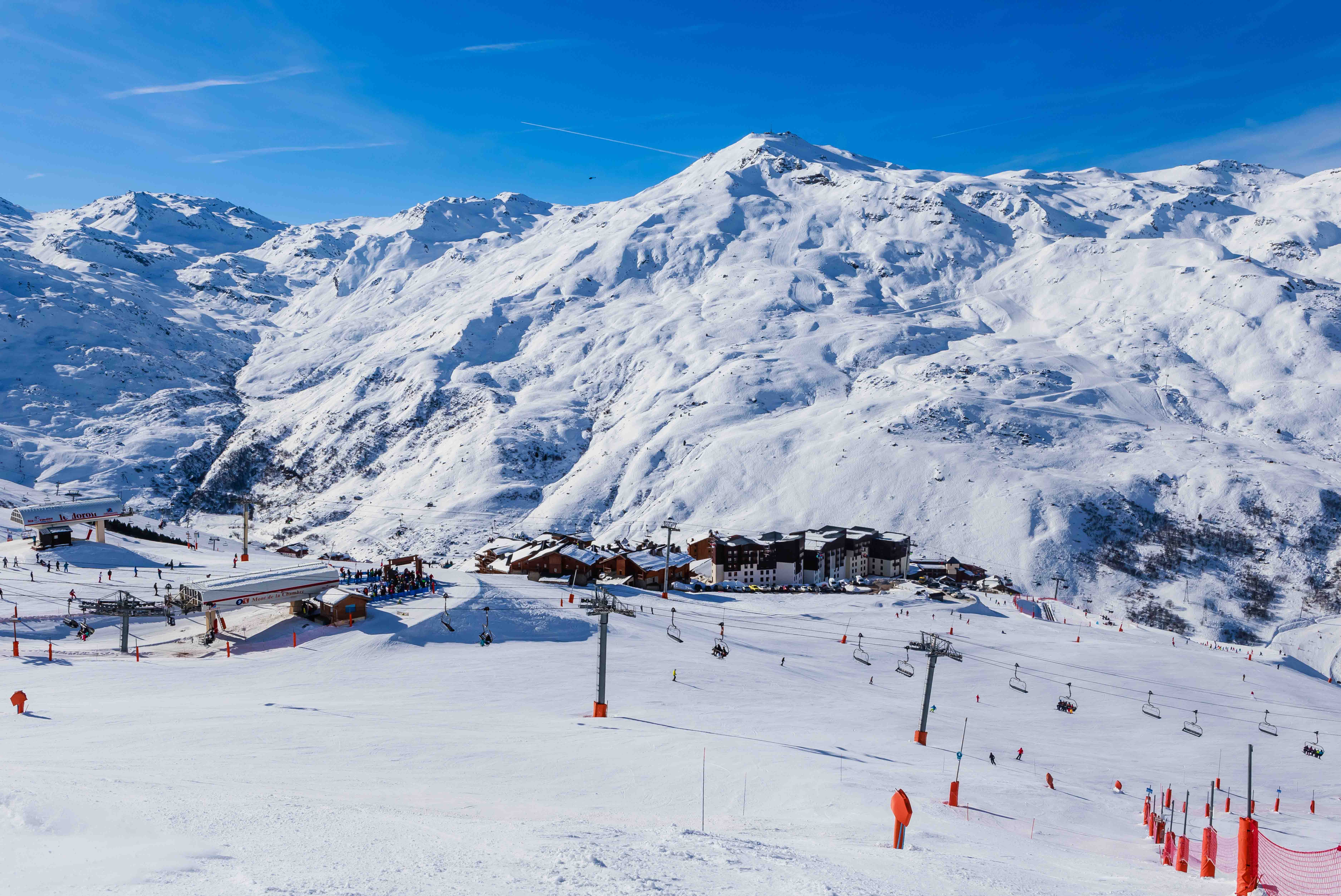 Rejs til Val Thorens - Vinterlandskab med skiløjper og lifte i et sneklædt bjergresort, hvor skiløbere nyder solskinsvejr.