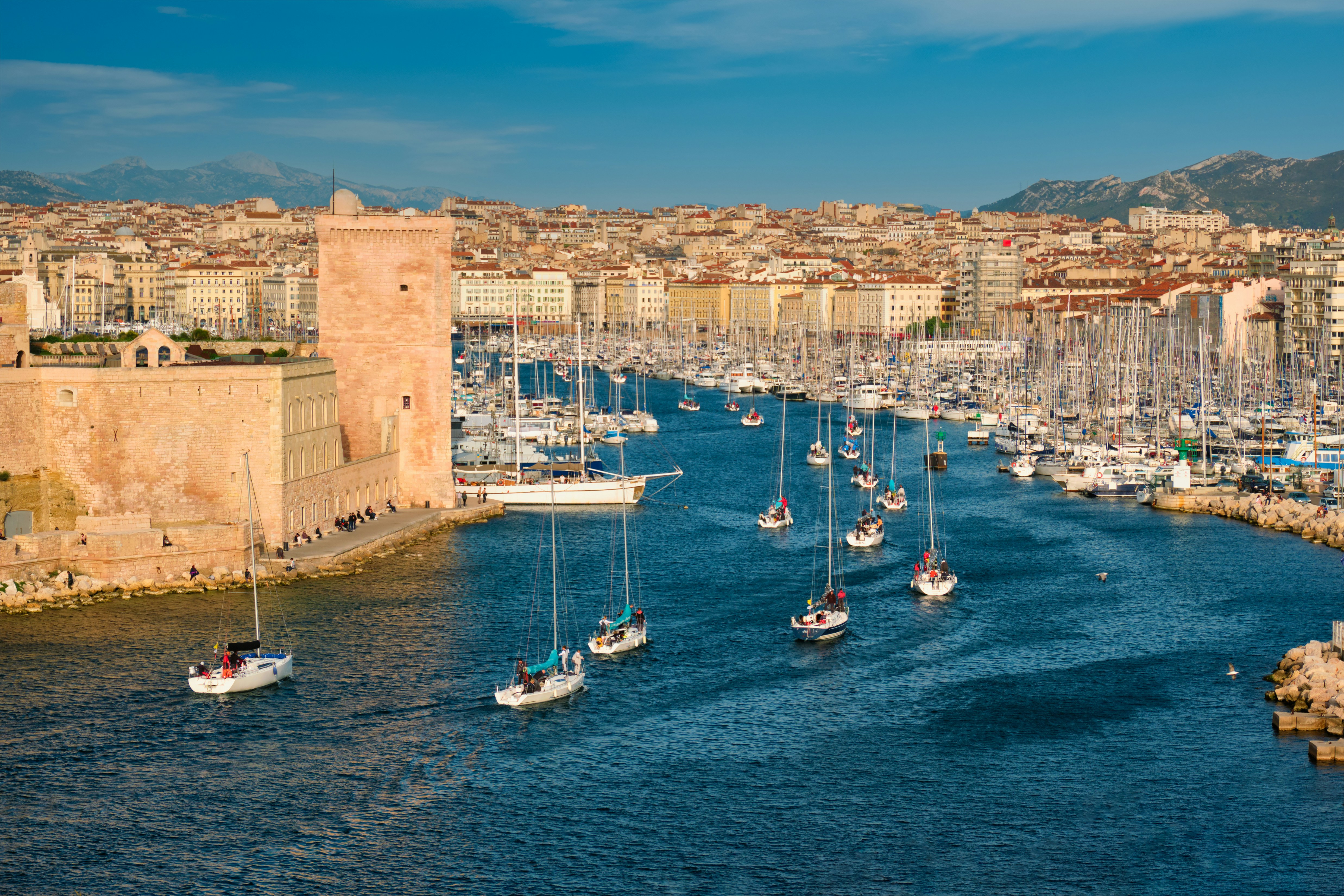 Harbor in the french riviera with boats on their way in with city in the background