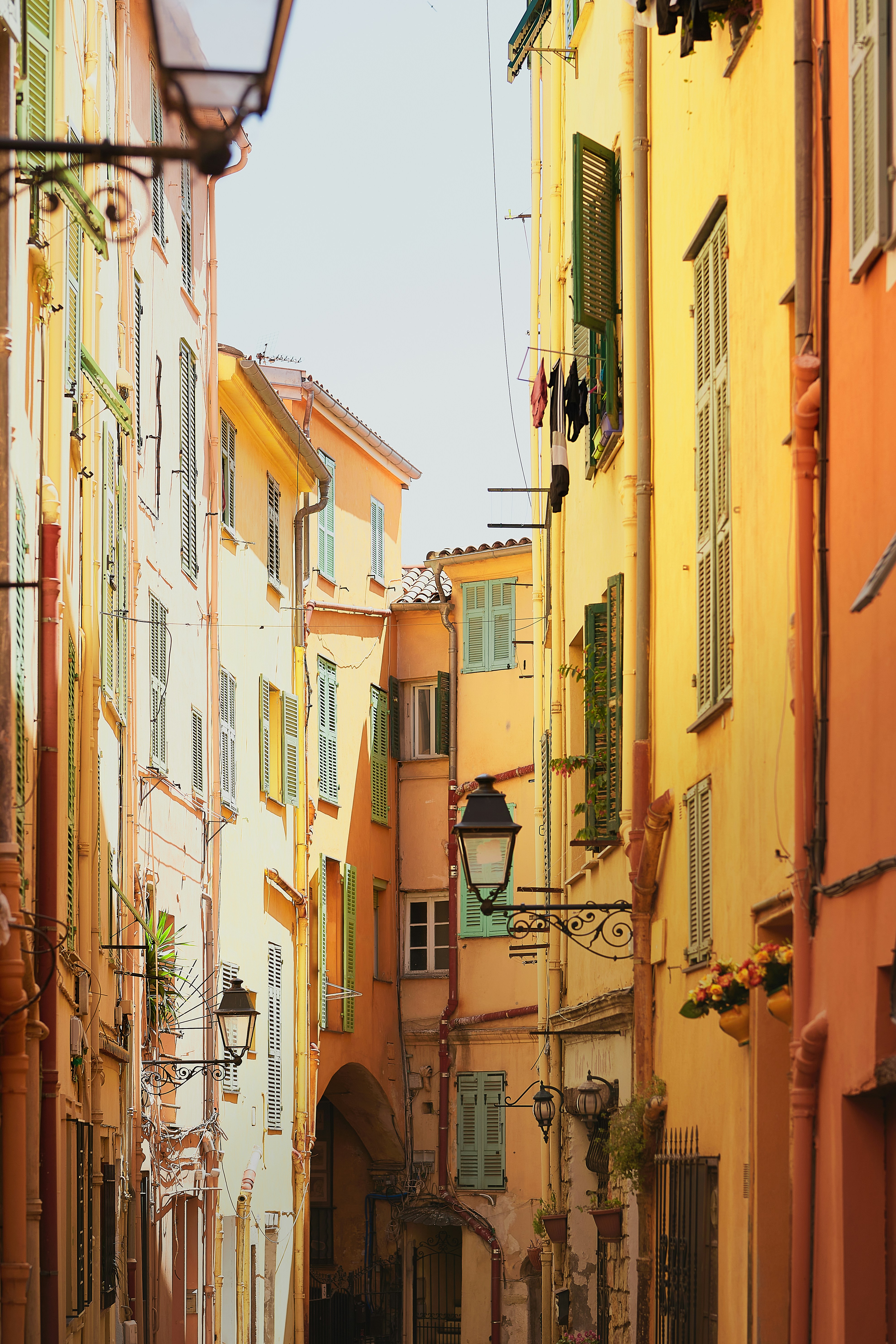 Smalle, farverige gader i en middelhavsby med pastelfarvede bygninger og skodder samt dekorative gadelygter