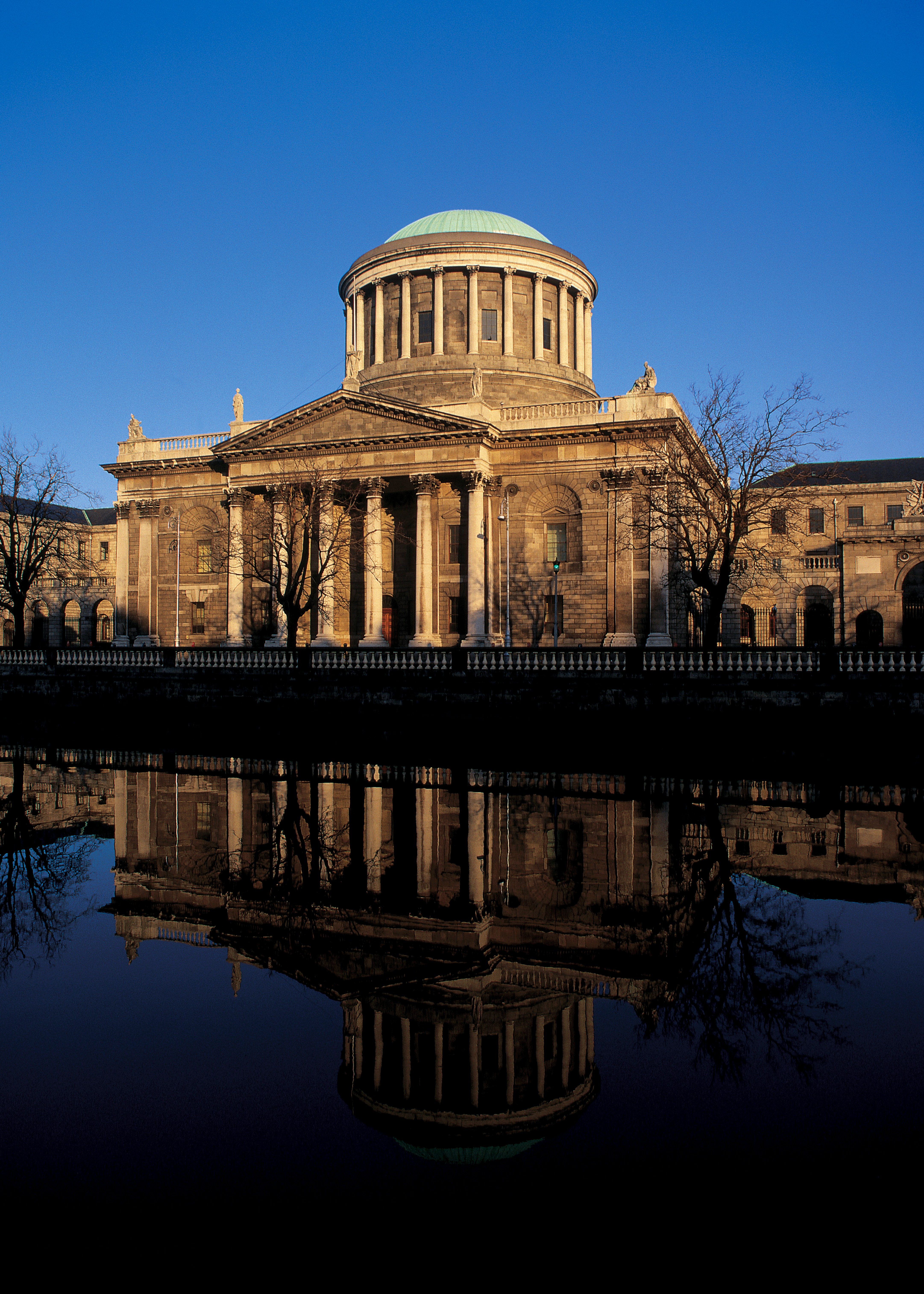 Historisk bygning med søjler og kuppel i reflekteret vand, blå himmel i baggrunden