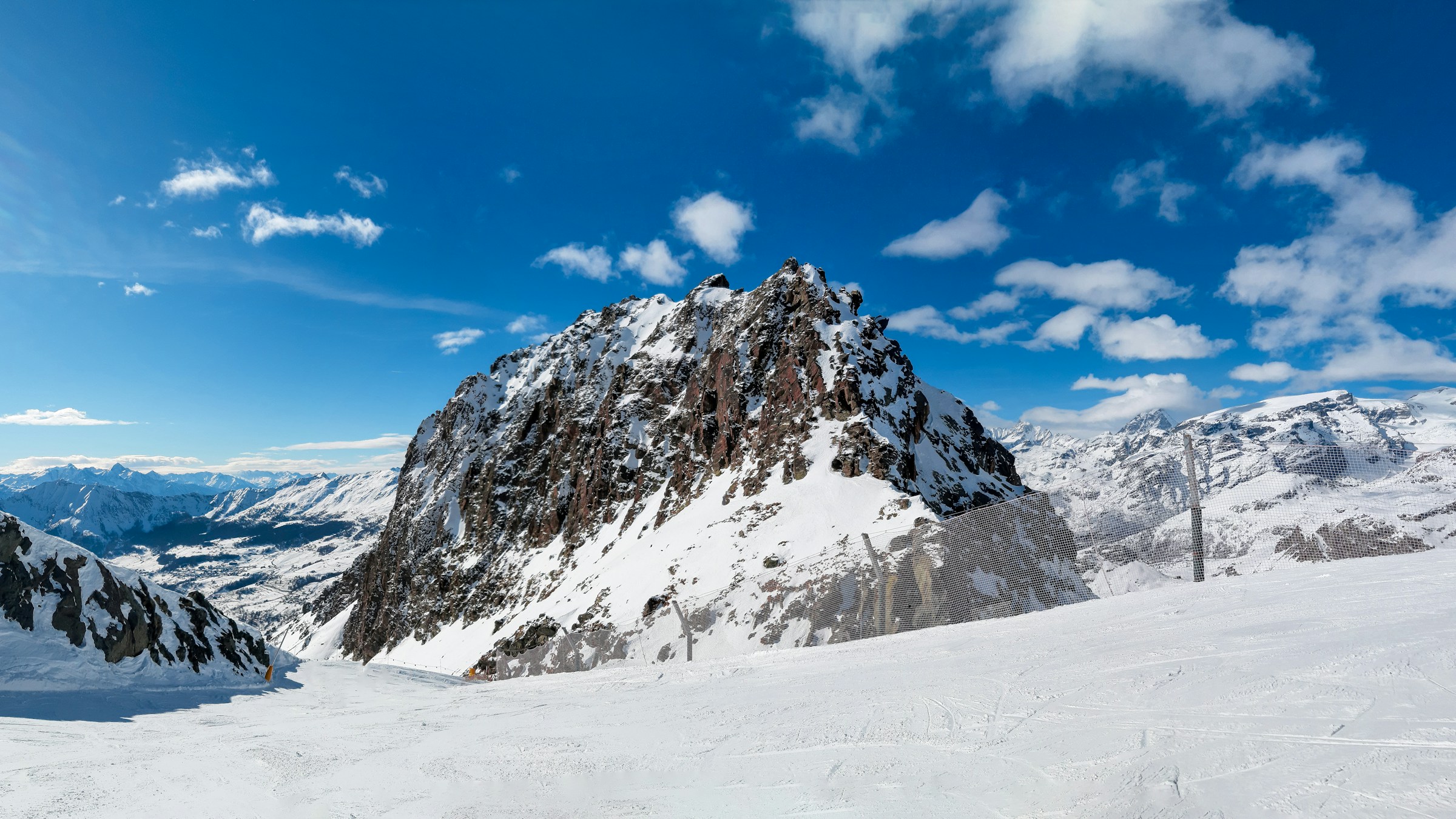 Sneklædte bjerge på en skiløjpe med blå himmel og skov i baggrunden i Champoluc, Italien