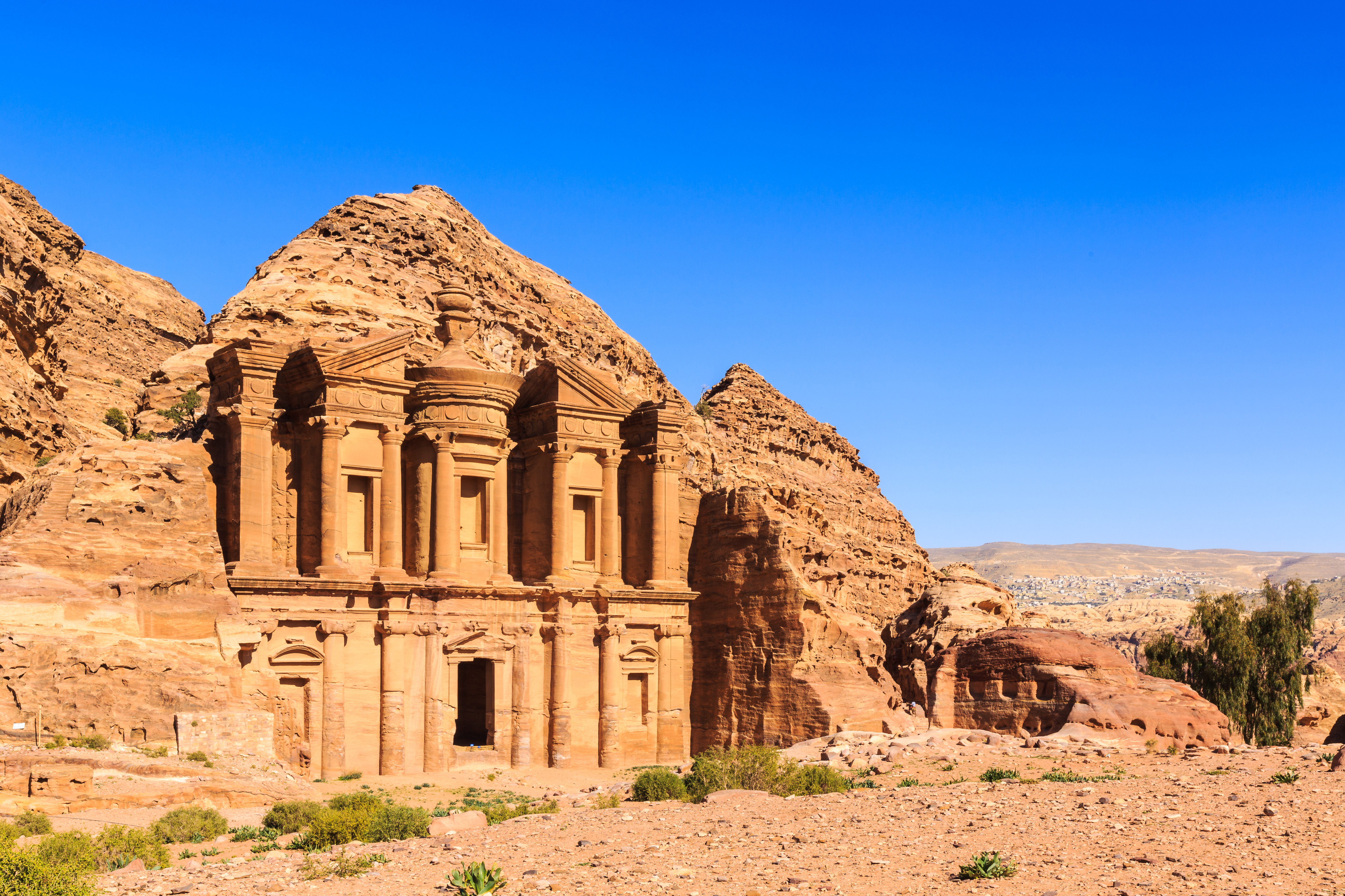 Oldtidsbyen Petra i Jordan med Al-Deir klosteret udskåret i sandsten, set under en klar blå himmel