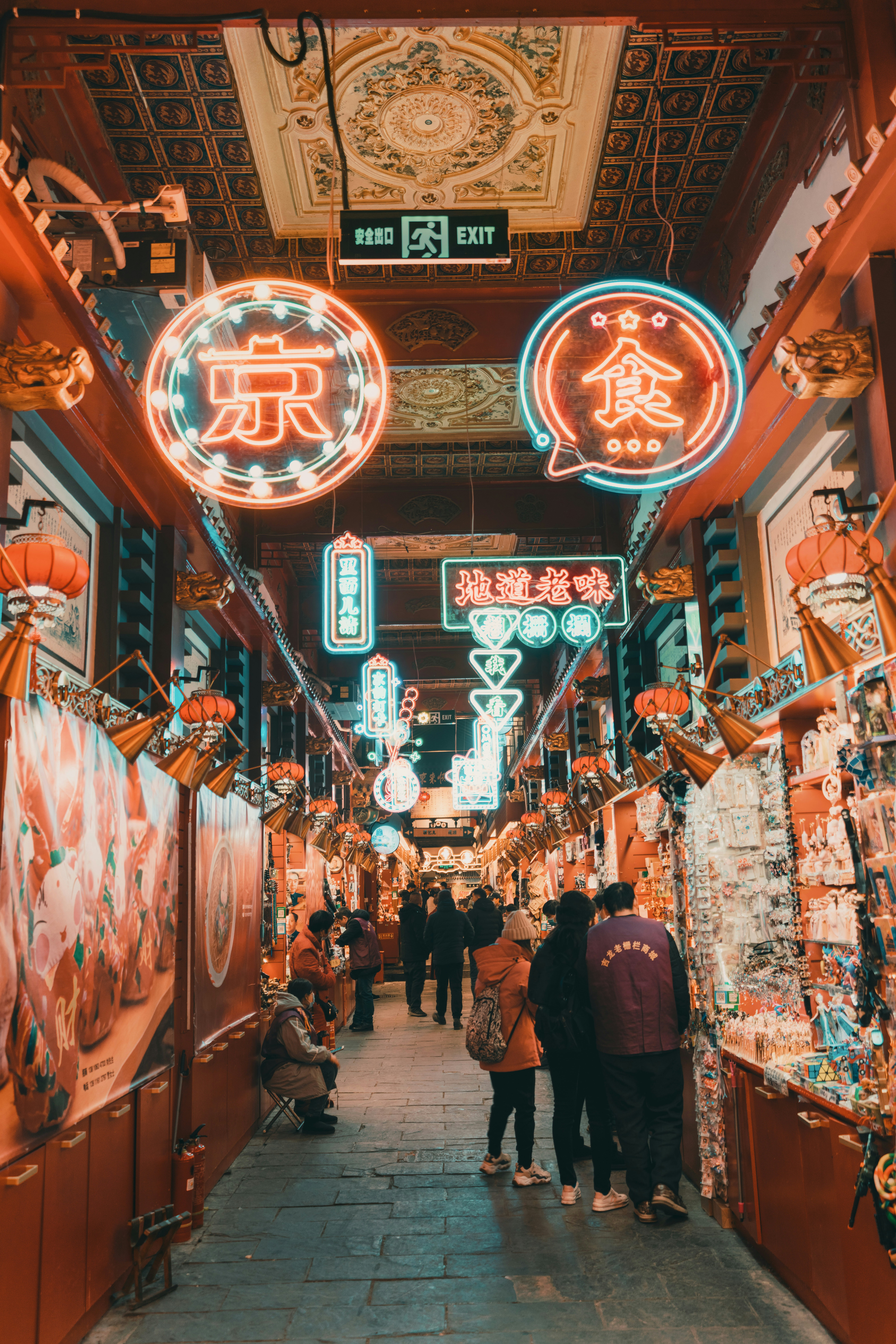 Folk går gennem et levende gademarked i Beijing om natten, oplyst af farverige neonskilt og traditionelle dekorationer