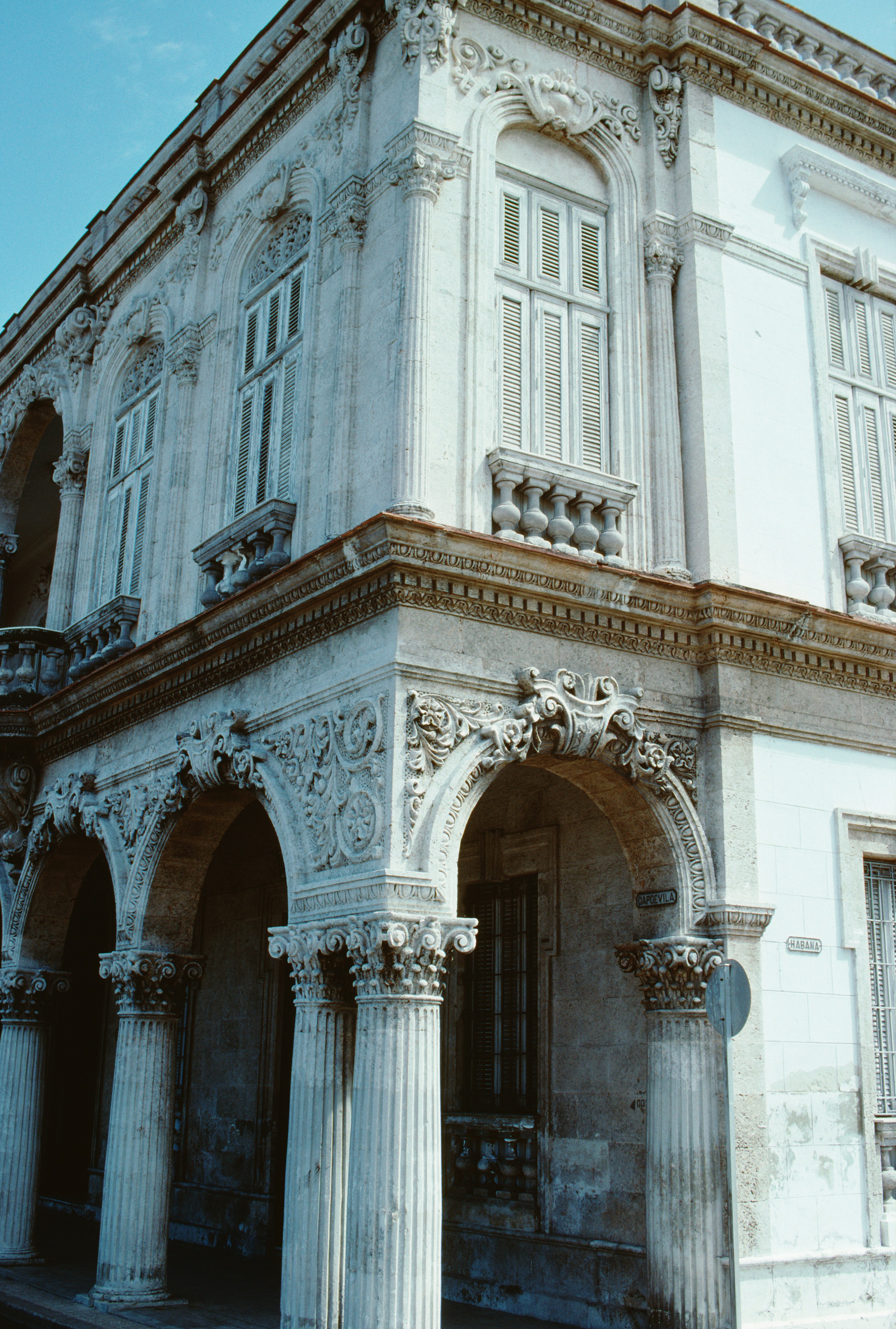 Historisk bygning facade med udsmykkede søjler og buer, der har indviklede stenhuggerier og klassiske arkitektoniske detaljer