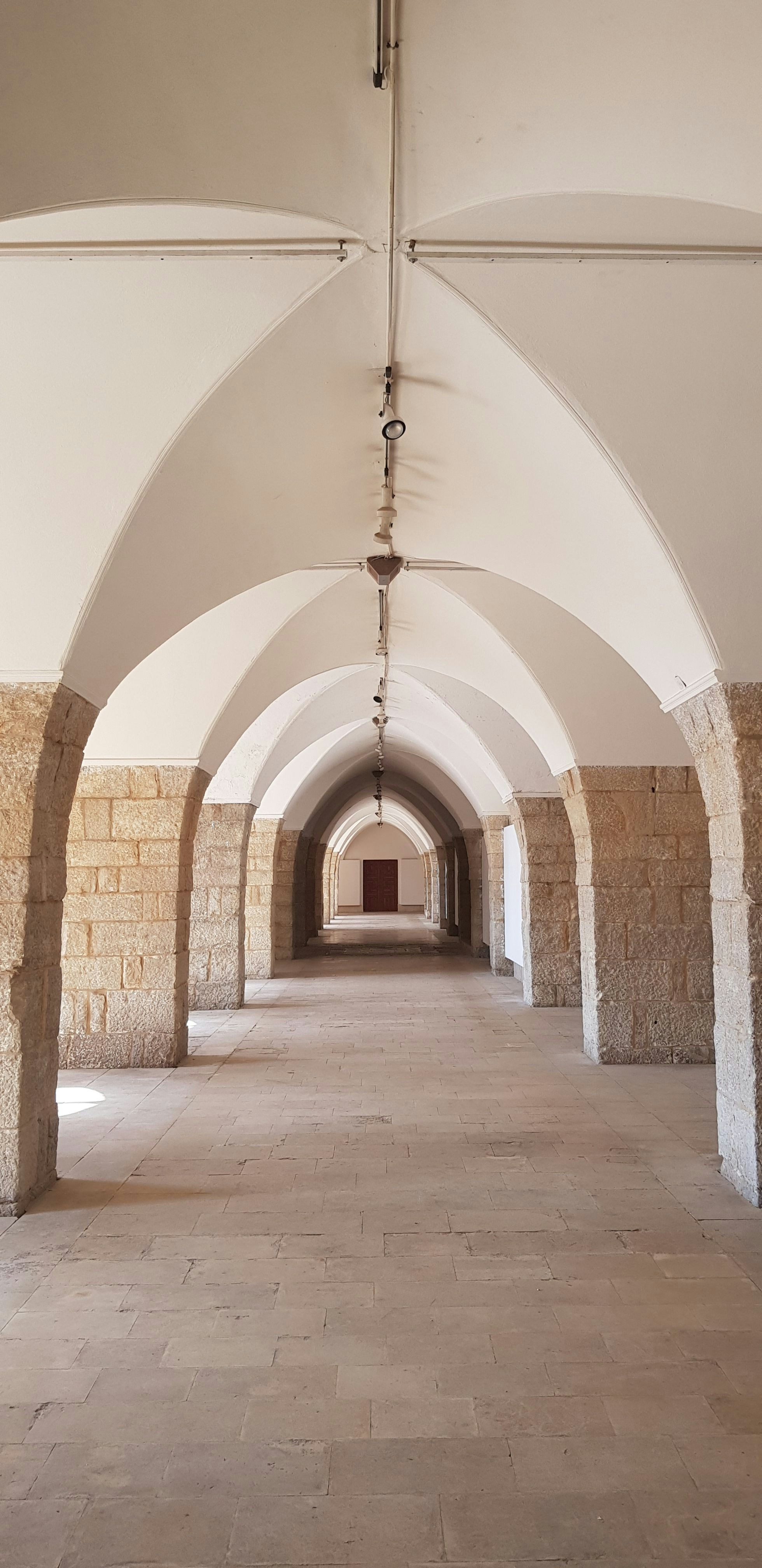 Bueformet stenhall med symmetriske søjler og hvælvet loft