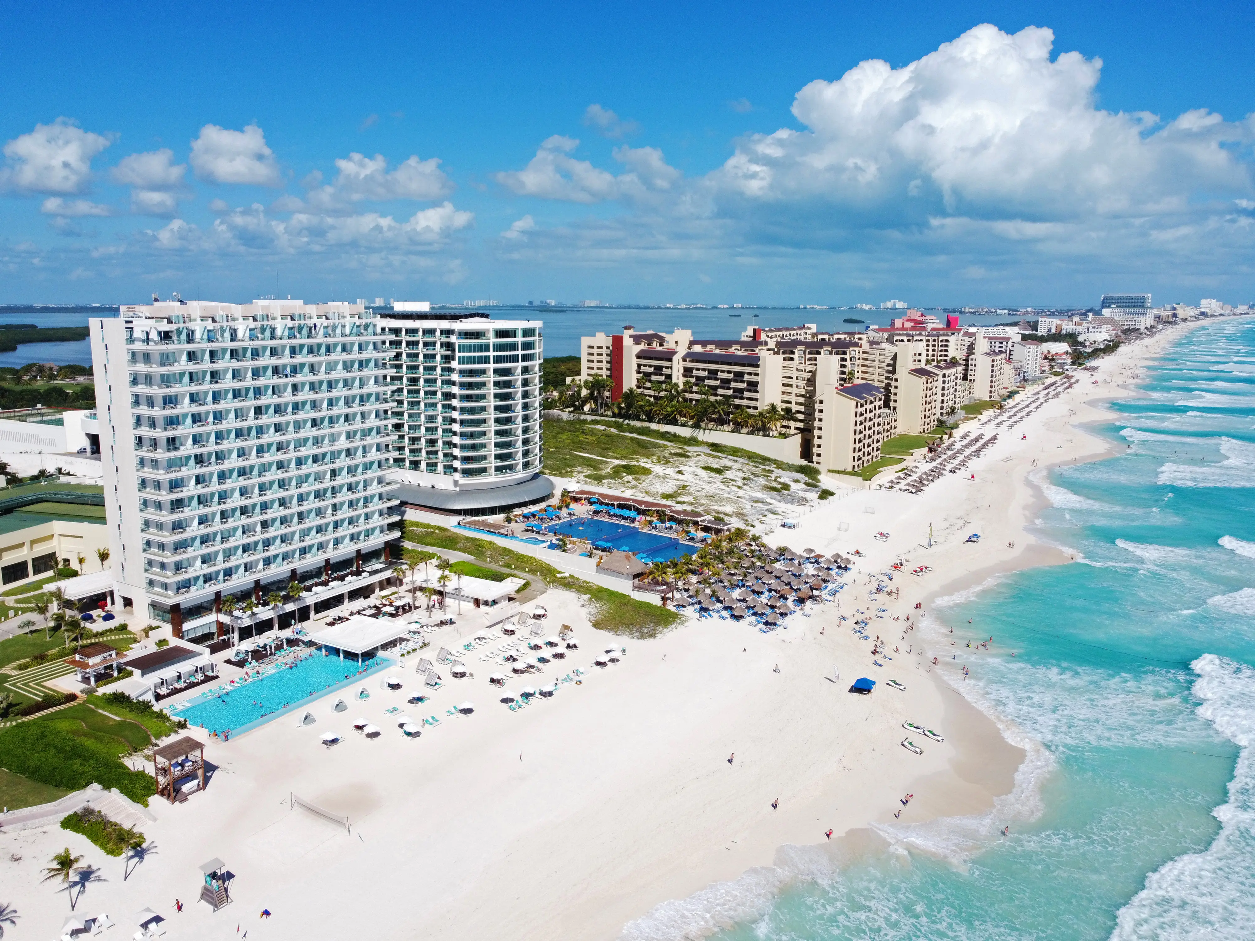 Luftfoto af strandresort ved Cancún, Mexico med hvidt sand, turkisblåt hav og moderne hoteller langs kysten.