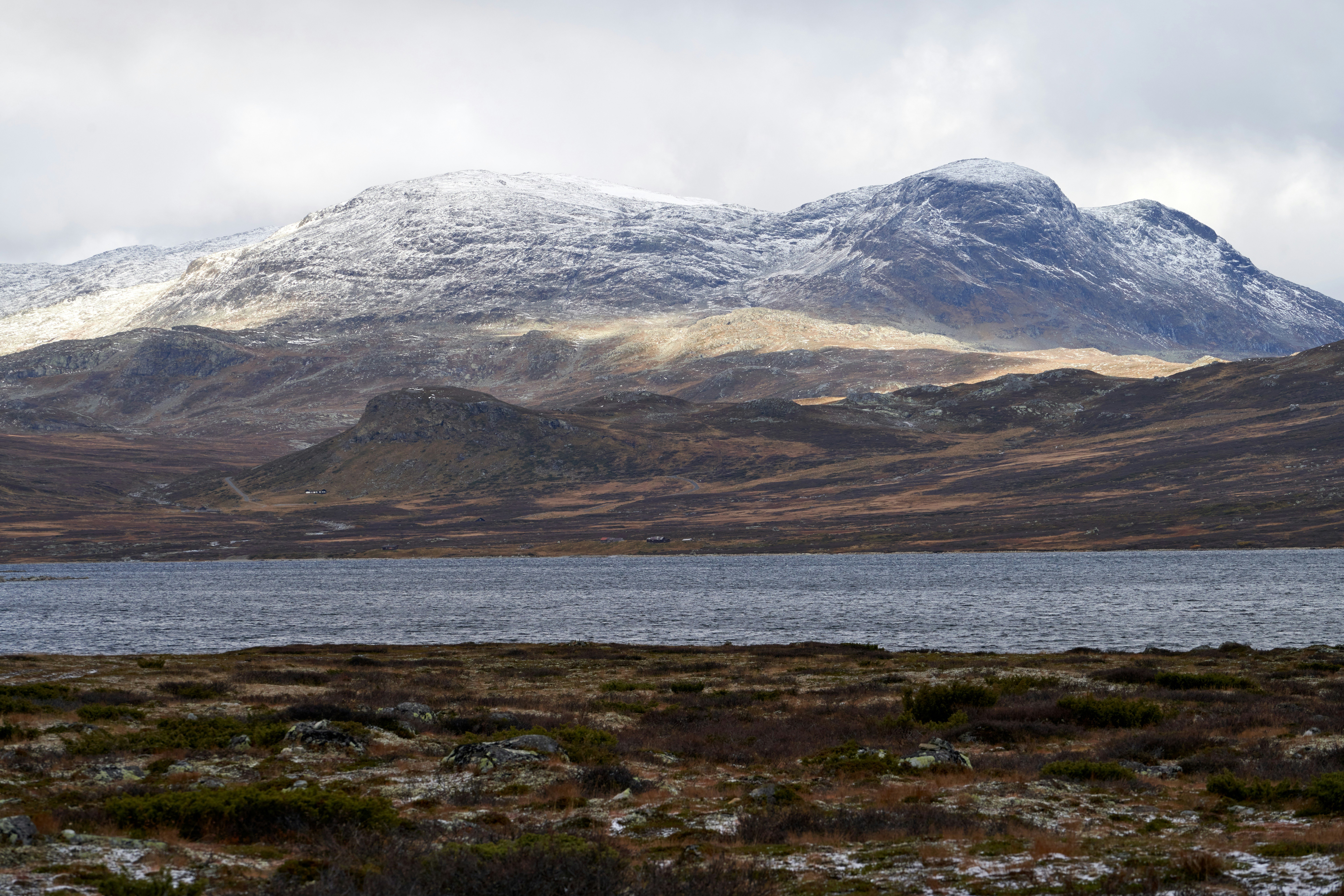 Rejs til Hemsedal - Udsigt over å, fjord og sneklædte fjelde i Norge med hvid himmel i baggrunden