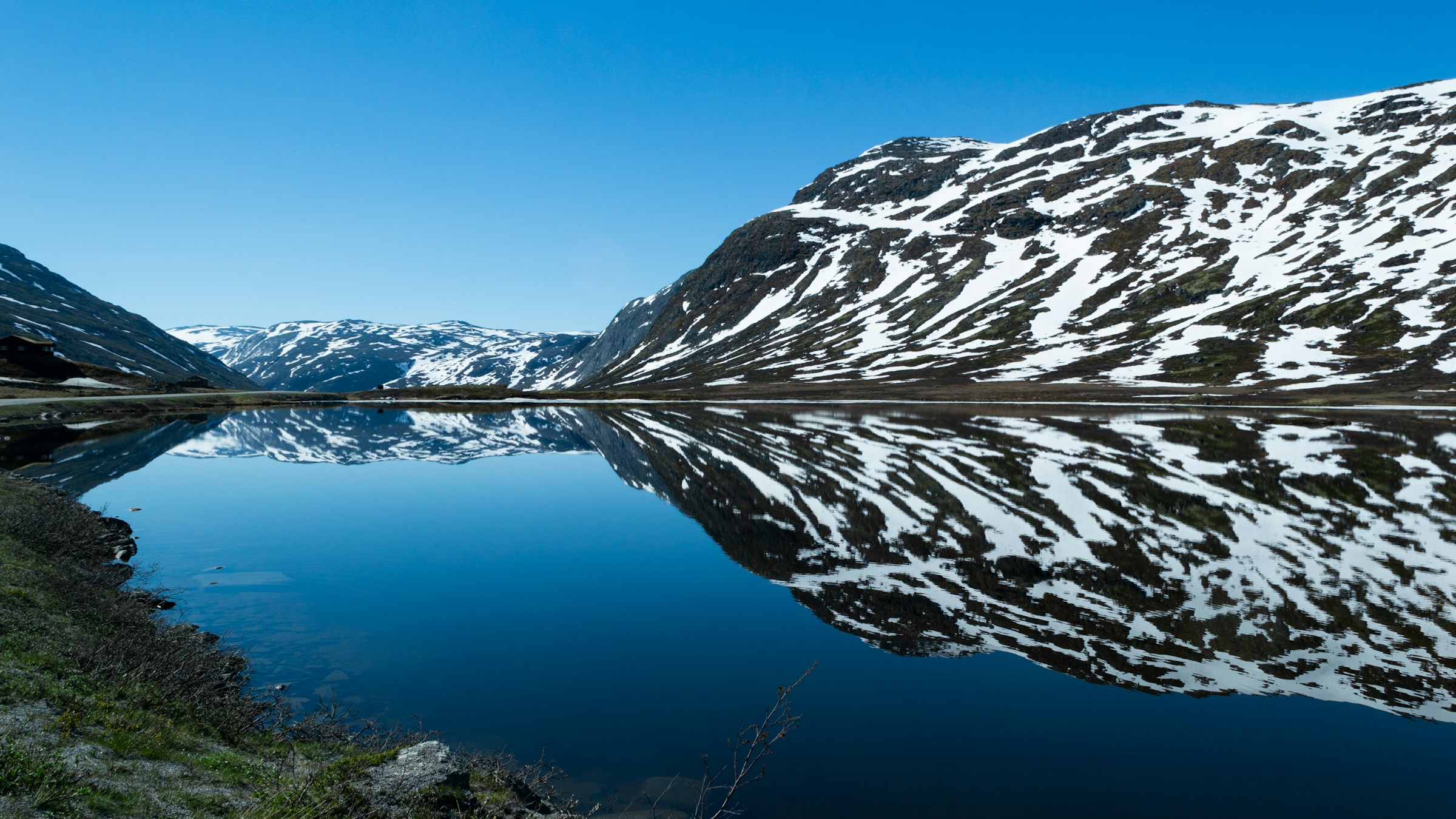 Rolig sø op til den norske fjord i Hemsedal med blå himmel i baggrunden