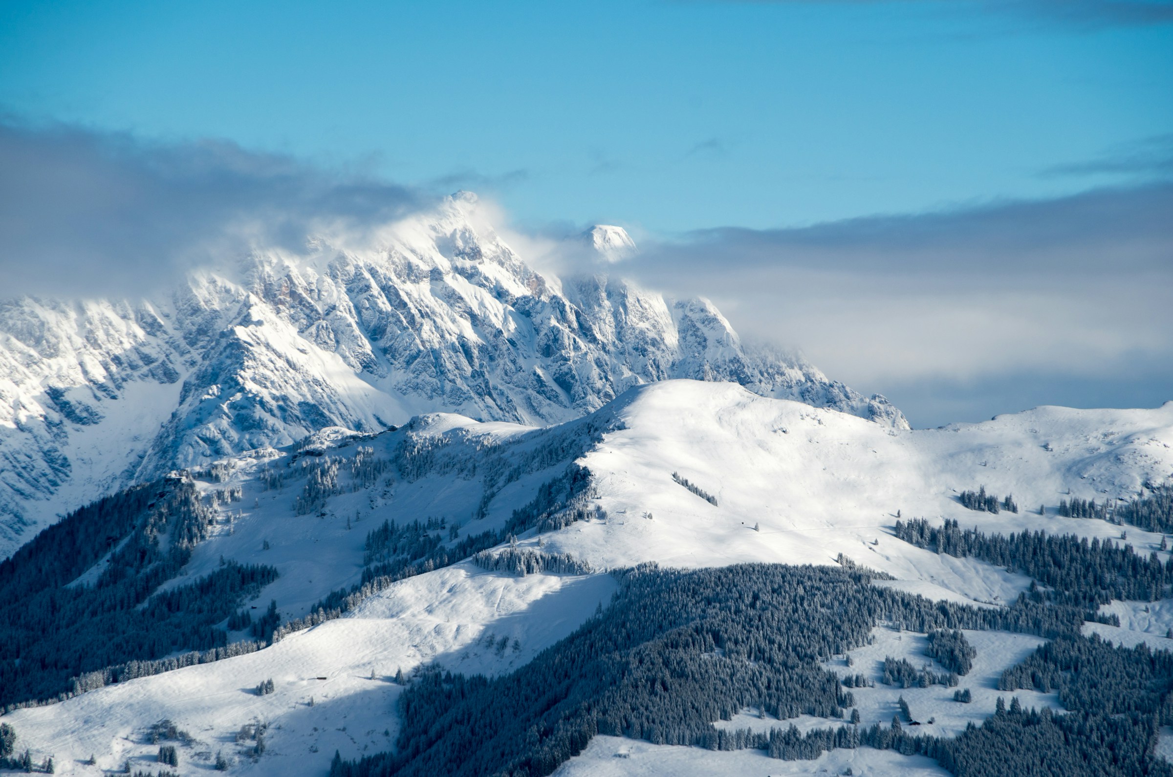 Sneklædt vinterlandskab og bjerge med blå himmel i baggrunden i skisportsstedet Zell am See, Østrig