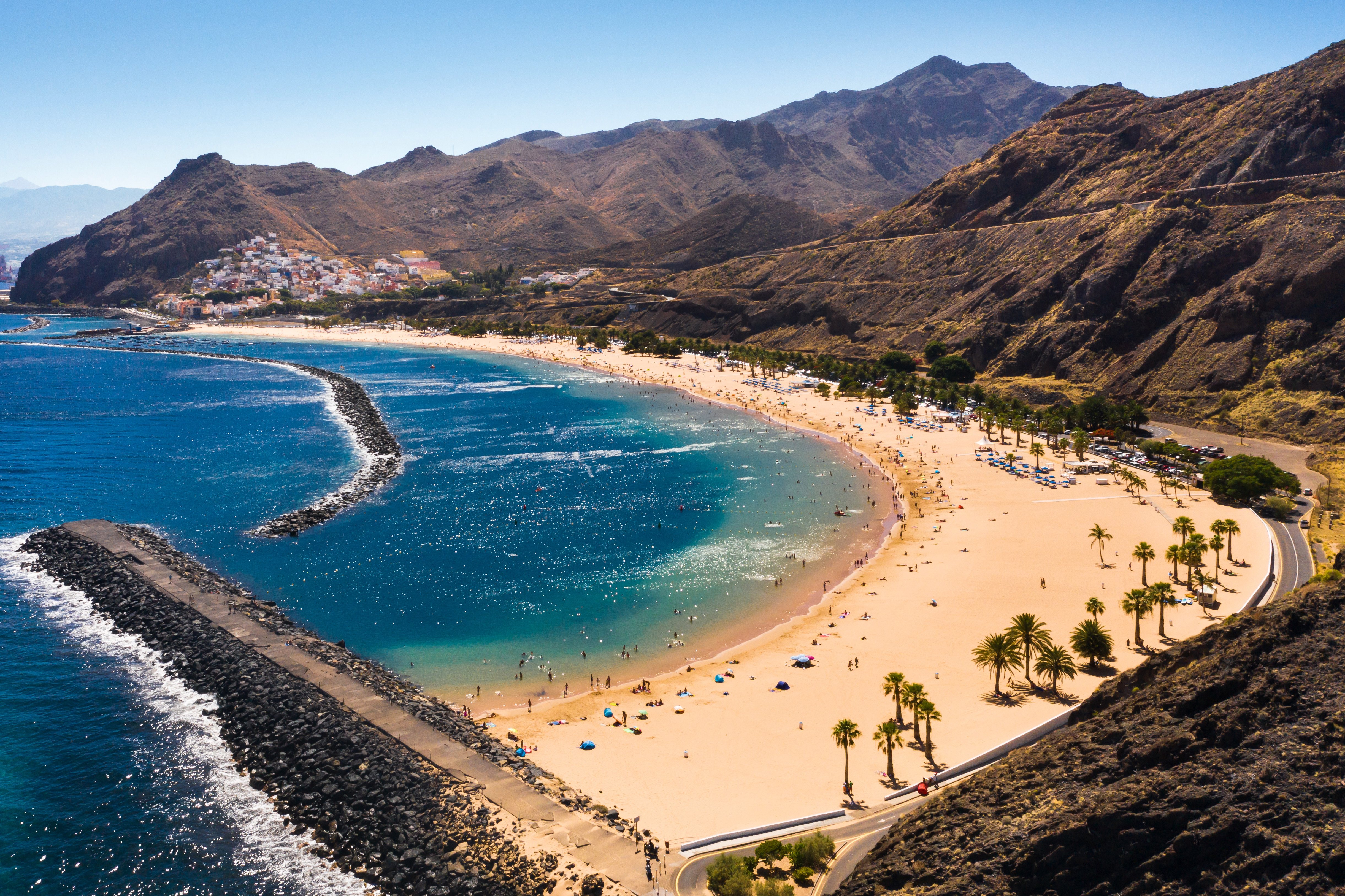 Travel to Canary Islands - Blue sea beach surrounded by mountains and greenery in the canary islands