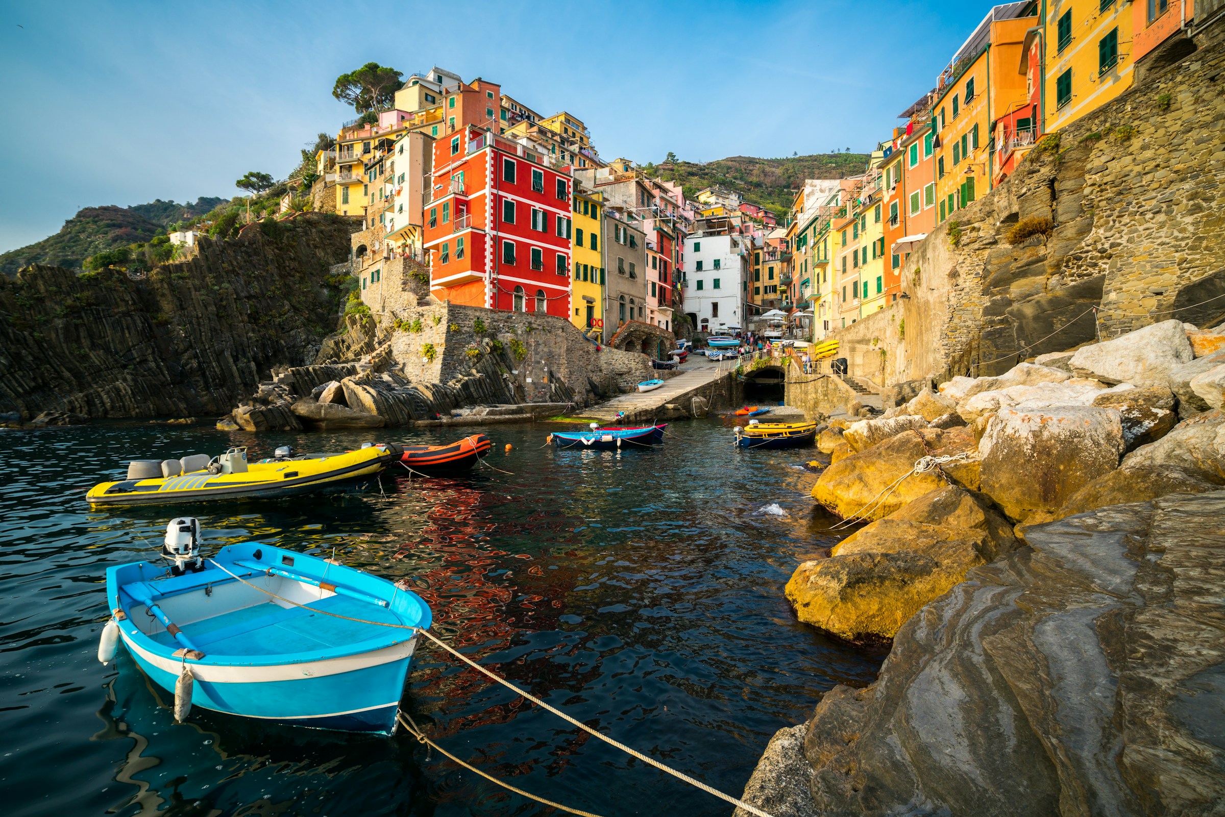 Farverige både og bygninger i den maleriske fiskerby Riomaggiore, en del af Cinque Terre, Italien, på en solrig dag