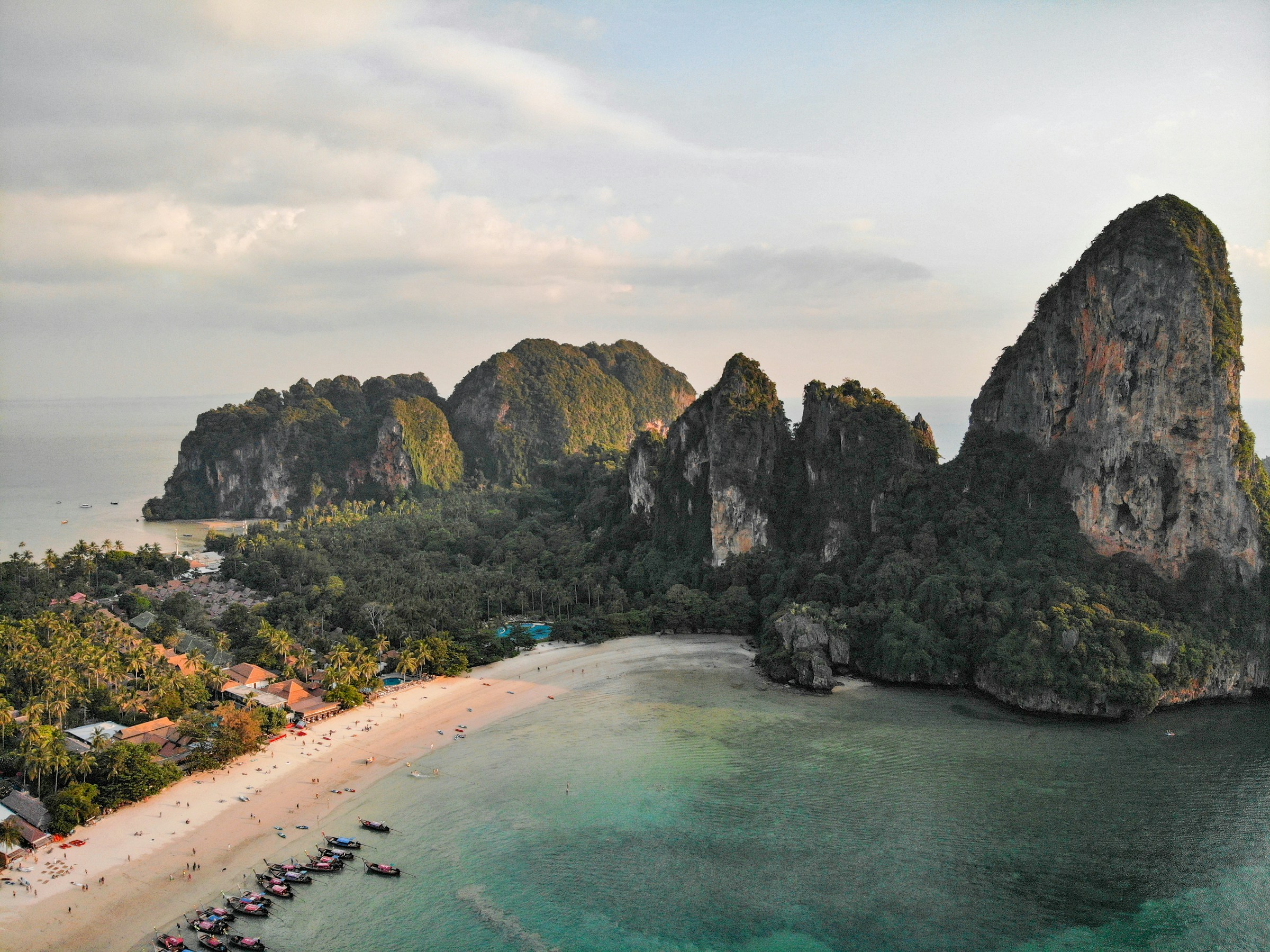 Aerial view of Railay Beach, Krabi, showcasing lush greenery, majestic limestone cliffs, and clear turquoise waters.