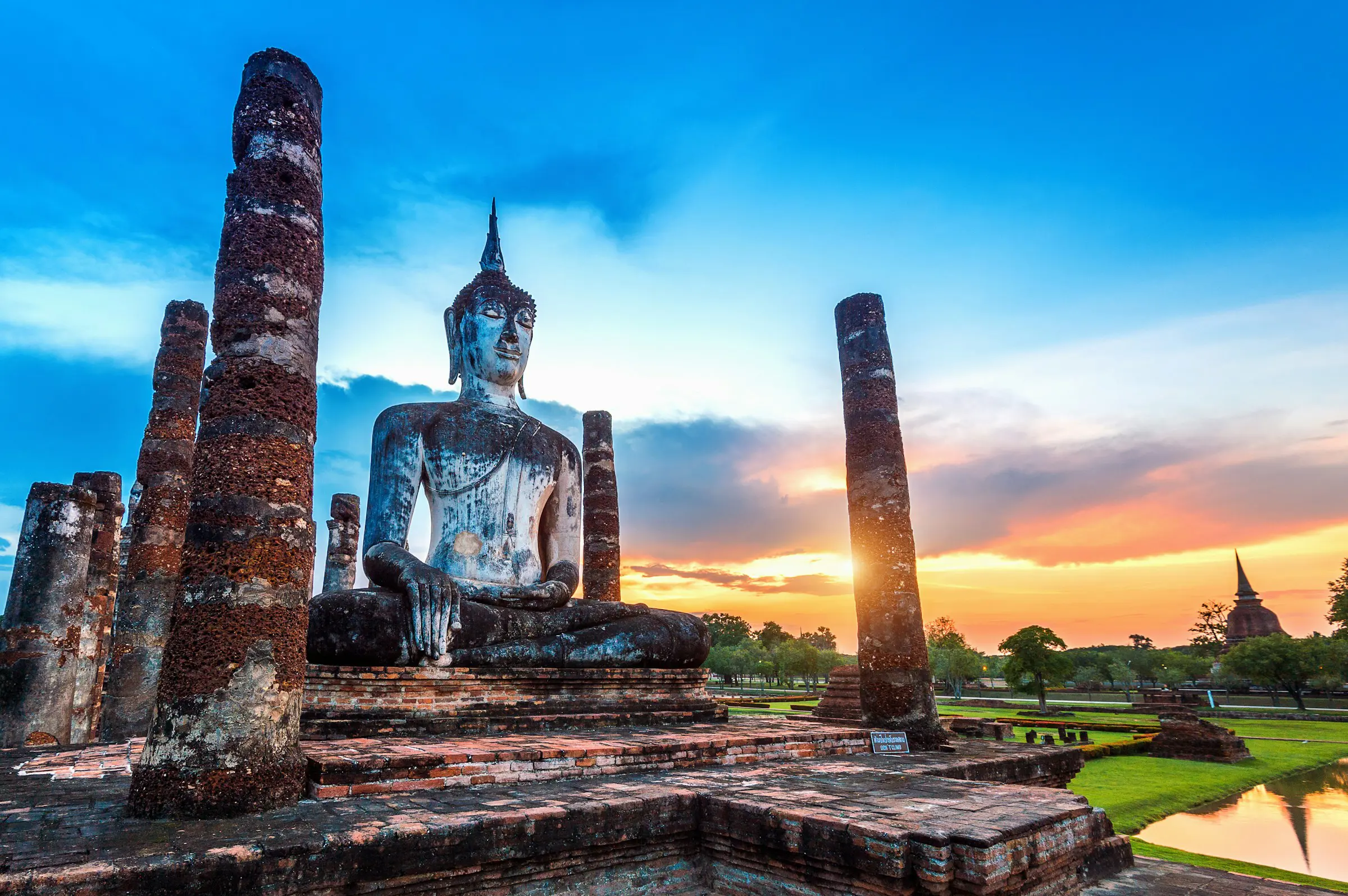 En Buddha-statue på en bakke omgivet af natur i skumringen i Thailand