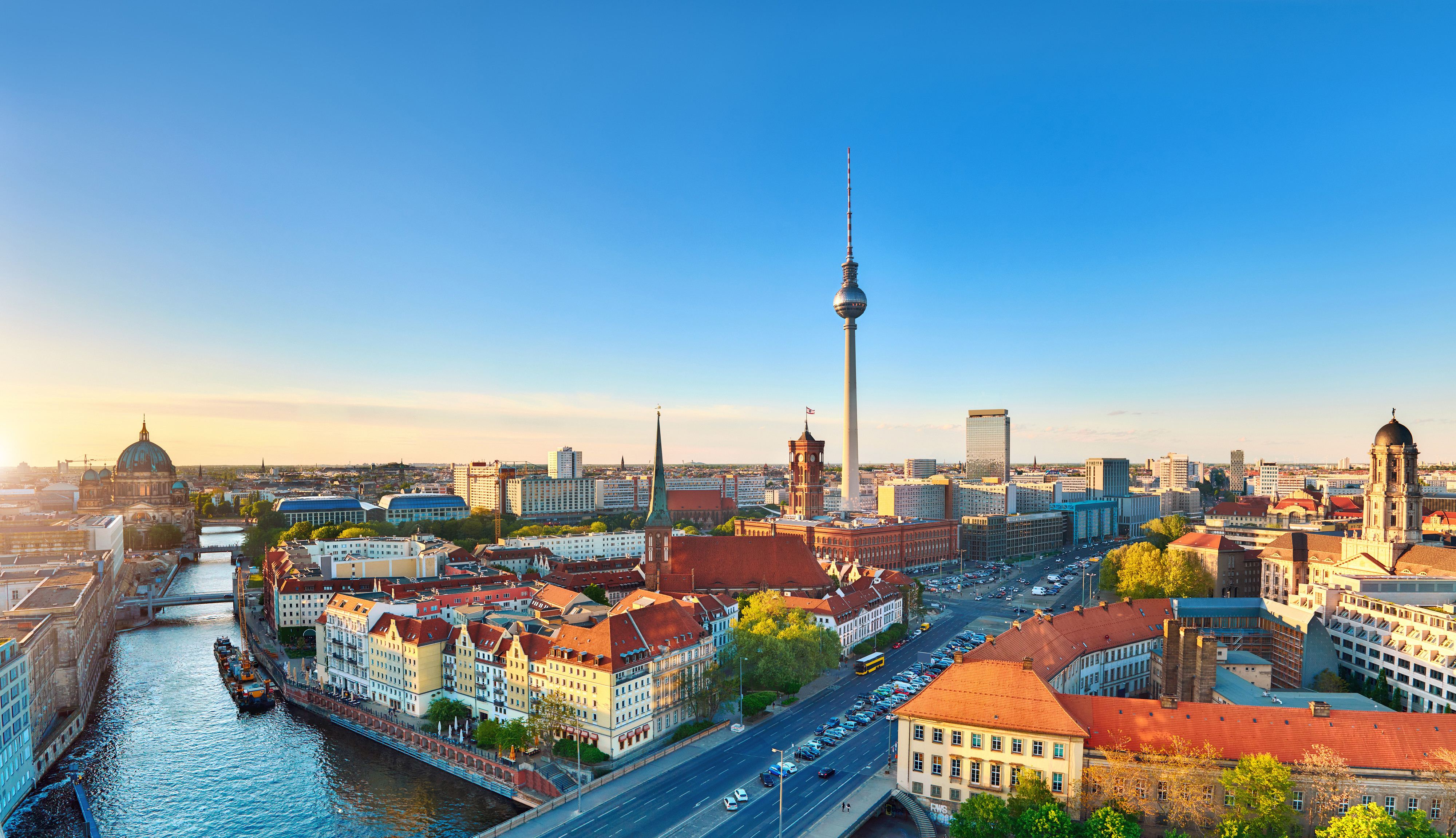 Luftfoto af Berlin, Tyskland ved solnedgang, med den ikoniske Berliner Fernsehturm og historiske bygninger langs Spree-floden under en klar blå himmel