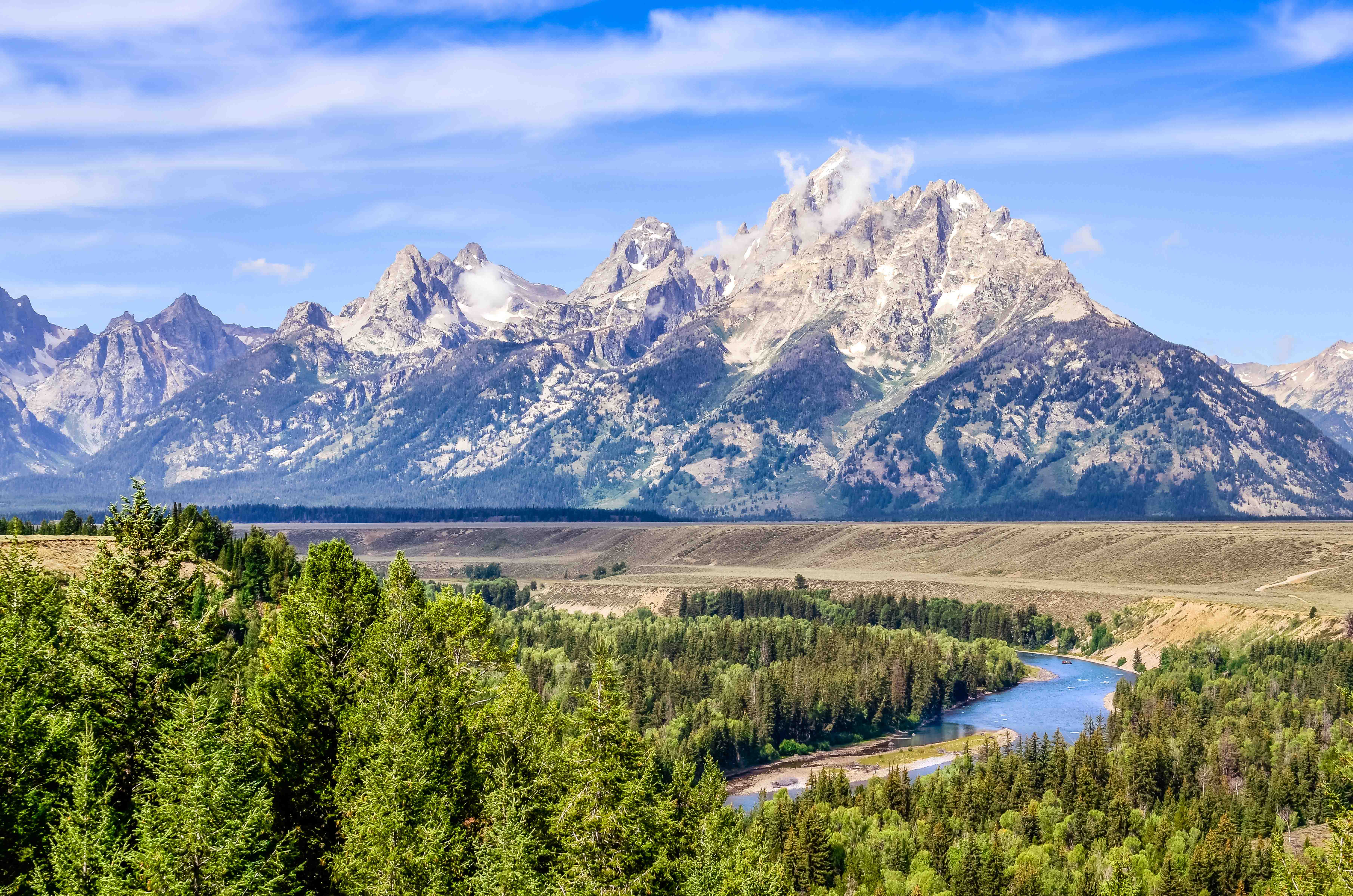 Tur til Jackson Hole - Udsigt over Teton-bjergene med flod og nåleskov under en klar blå himmel.
