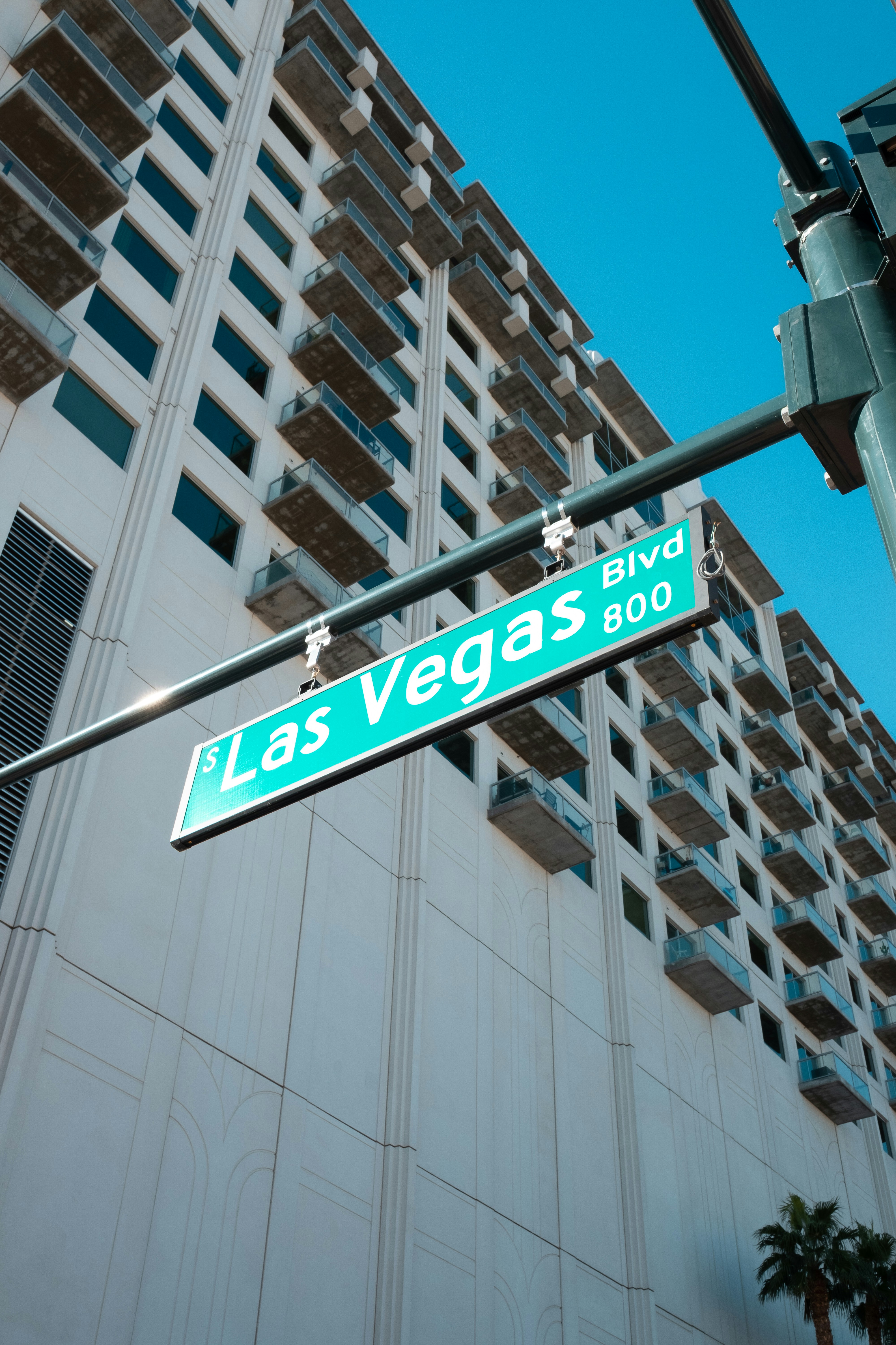 Gadeskilt for Las Vegas Blvd med en høj bygning i baggrunden mod en klar blå himmel